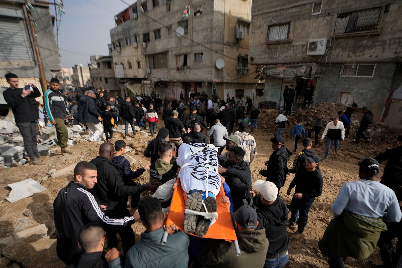 Mourners carry the bodies of eight killed Palestinians, some are wrapped with the Islamic Jihad flag, during their funeral following the withdrawal of the Israeli army, in the West Bank city of Tulkarem, Thursday, Dec. 26, 2024. (AP Photo/Matias Delacroix)