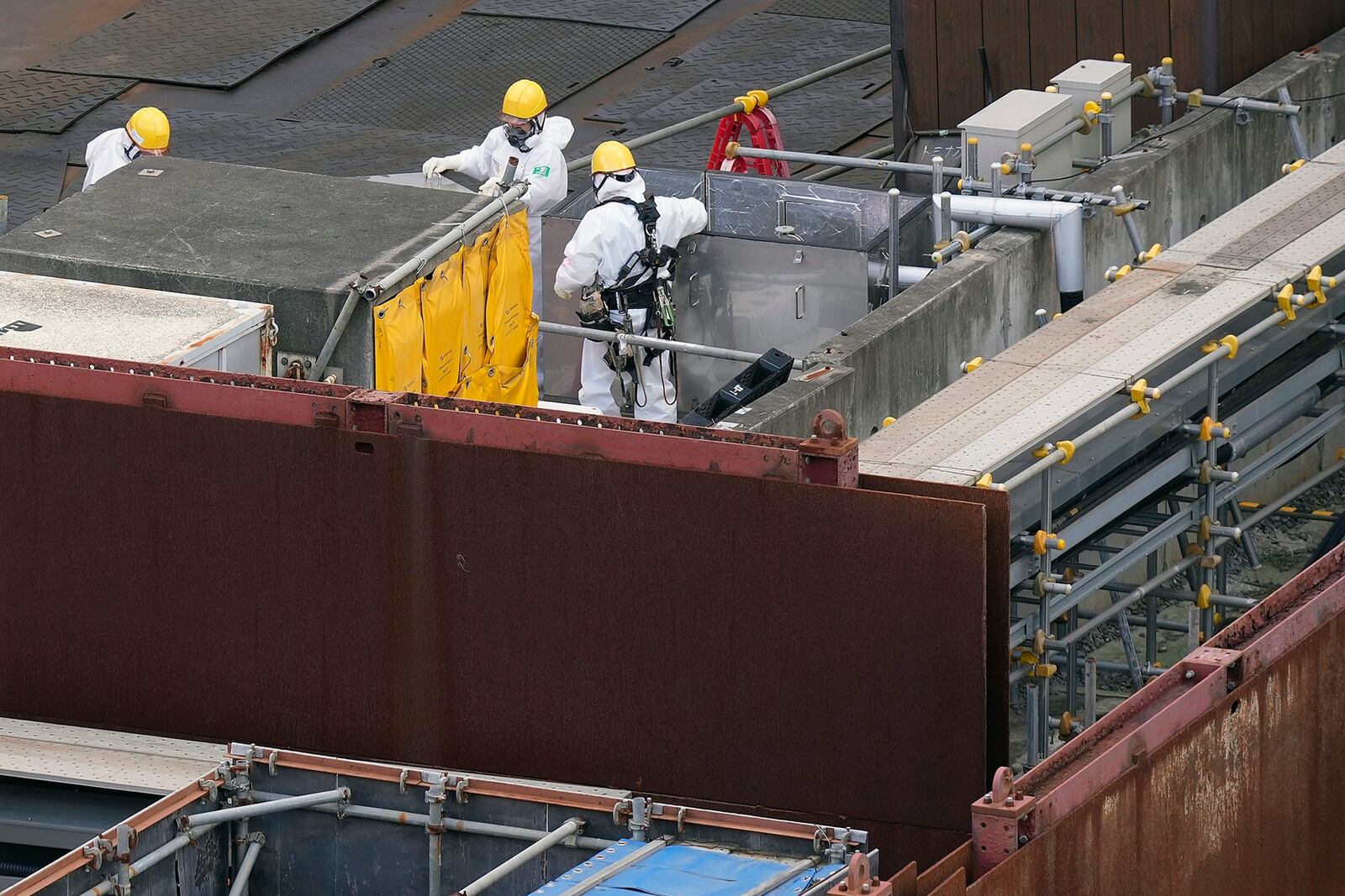 Workers in hazmat suits are seen at the Fukushima Daiichi nuclear power plant, operated by Tokyo Electric Power Company Holdings (TEPCO), in Okuma town, northeastern Japan on Monday Feb. 20, 2025. (AP Photo/Eugene Hoshiko)