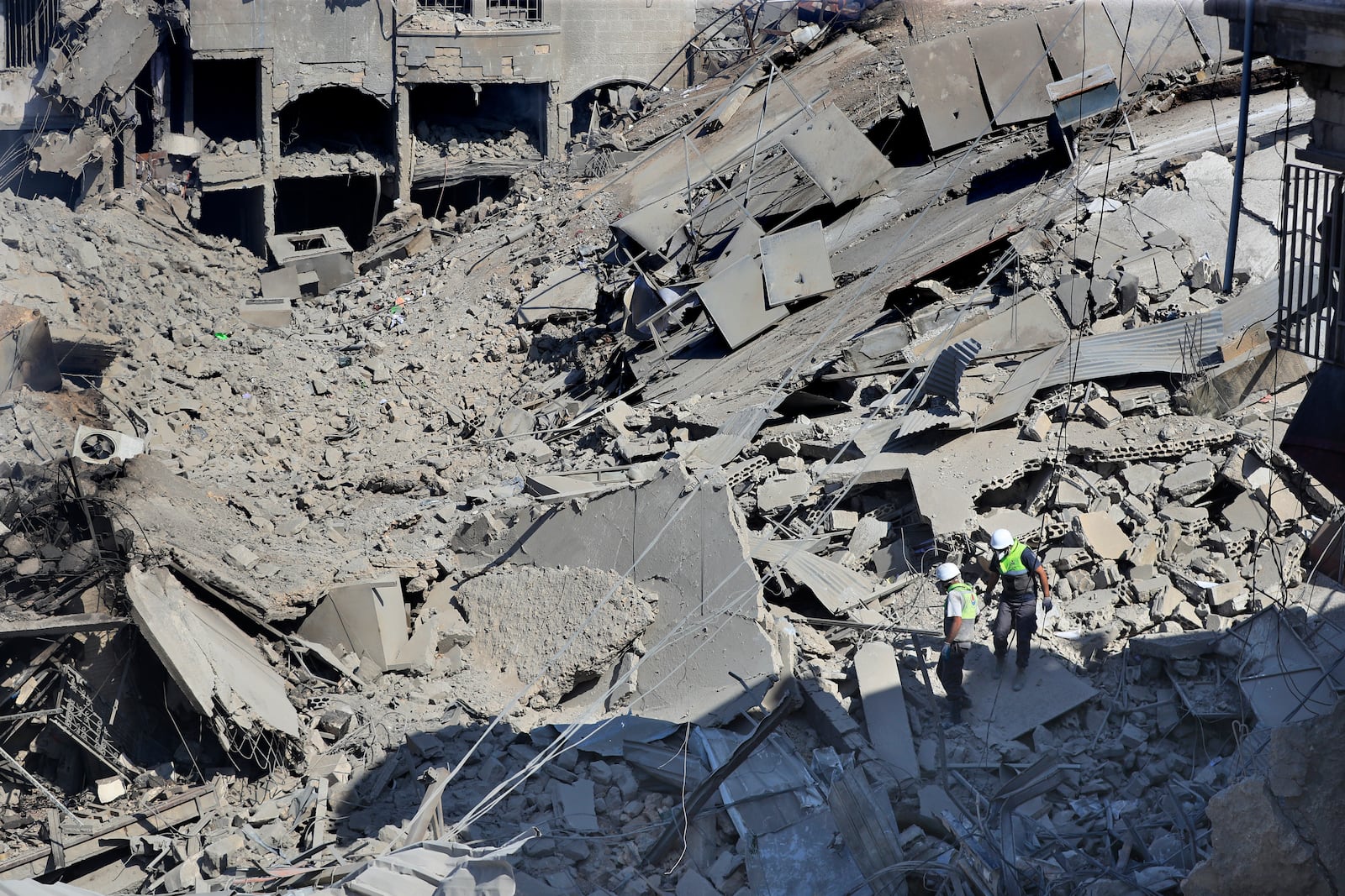 Hezbollah rescue workers search for victims amidst the rubble of destroyed buildings at a commercial street that was hit Saturday night by Israeli airstrikes, in Nabatiyeh town, south Lebanon, Sunday, Oct. 13, 2024. (AP Photo/Mohammed Zaatari)