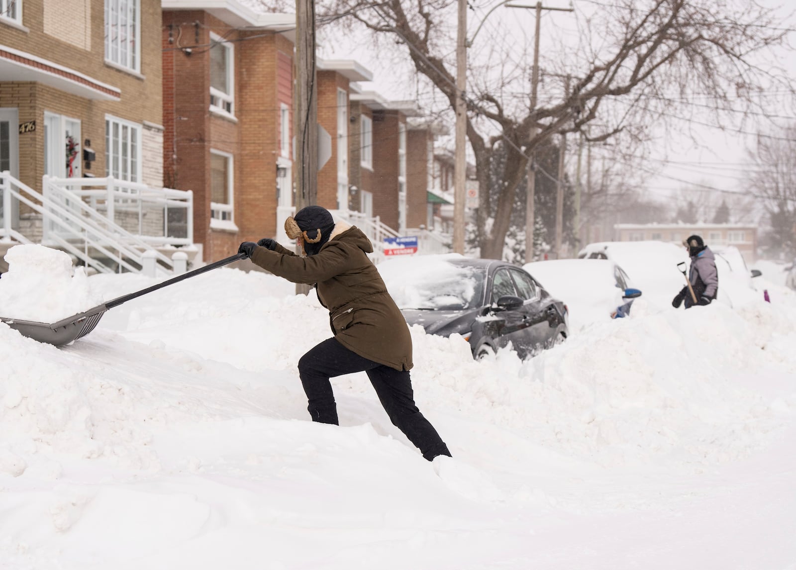 People shovel snow to dig out their cars in Montreal, Monday, Feb. 17, 2025, after over 70 centimetres of snow fell in 4 days, breaking a snowfall record in the city. (Christinne Muschi/The Canadian Press via AP)