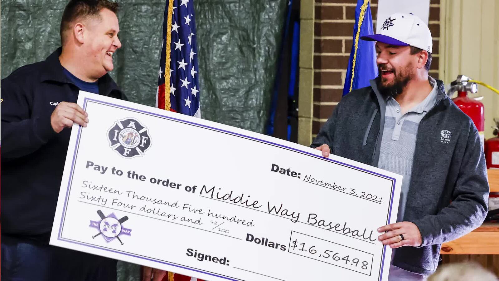 Middletown Division of Fire Captain Brian Wright presents a check to Kyle Schwarber, Middletown native and Major League Baseball player, on behalf of The Middletown Firefighters Association to The Middie Way Baseball, an organization focused on helping area youth learn the game of baseball, during a ceremony Wednesday, Nov. 3, 2021 at the Middletown Division of Fire headquarters. NICK GRAHAM / STAFF