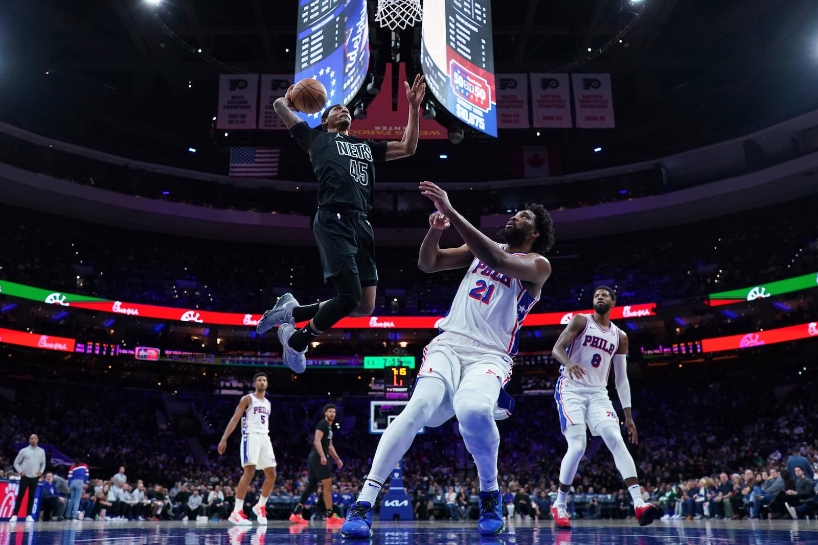 Brooklyn Nets' Keon Johnson, left, goes up for a dunk past Philadelphia 76ers' Joel Embiid during the second half of an NBA basketball game, Saturday, Feb. 22, 2025, in Philadelphia. (AP Photo/Matt Slocum)