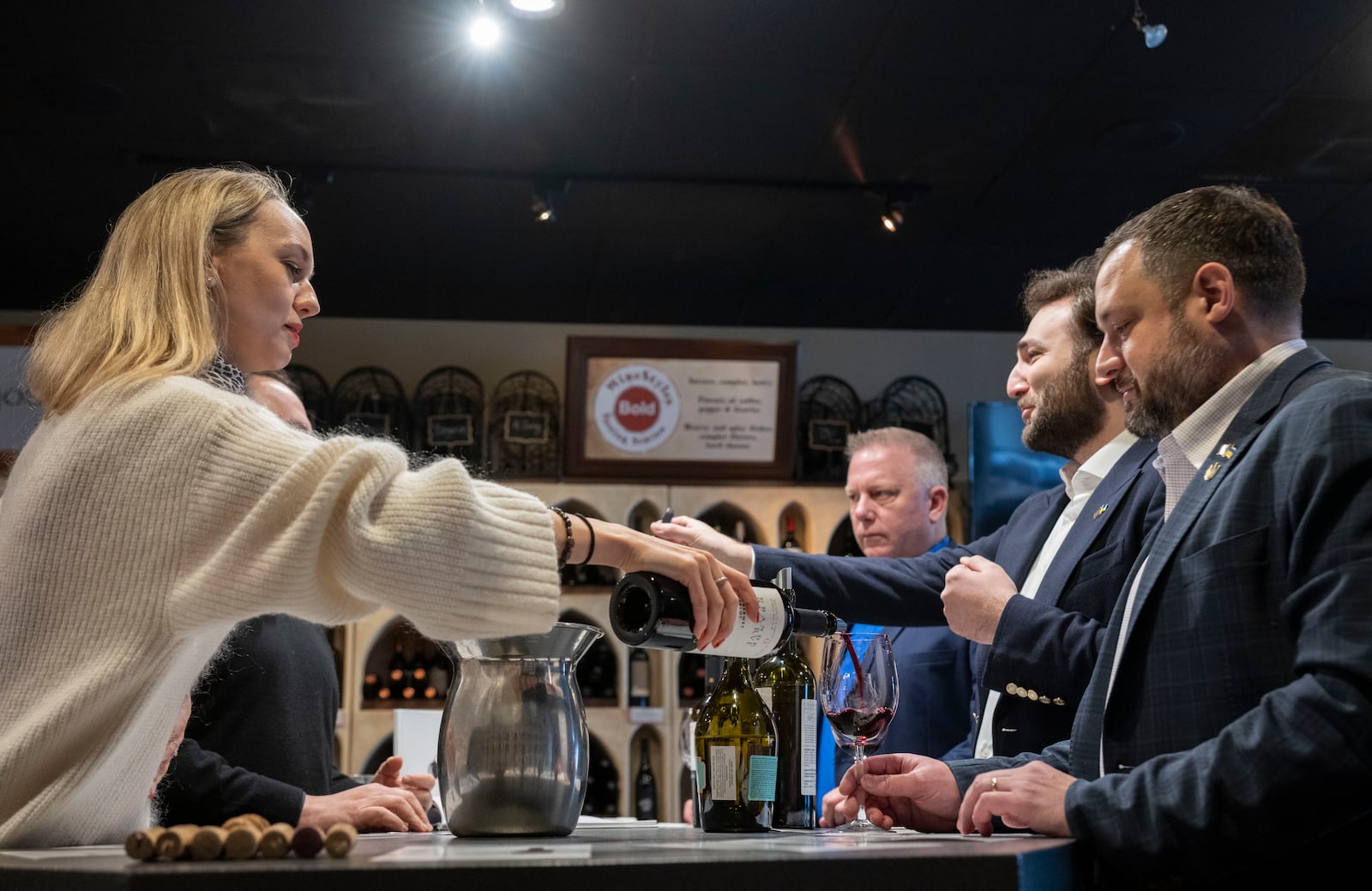 Valentyna Parsaieva, head of export for Shabo, a Ukrainian winery, left, pours a glass of wine for Sam Lerman, CEO of SPYRT Worldwide, right, during a wine tasting with Giorgi Iukuridze, owner and CEO Shabo, second from right, and Joseph Belli, Sales Manager for SPYRT Worldwide at Wine Styles, Dec. 20, 2024 in Dumfries, Va. (AP Photo/Kevin Wolf)