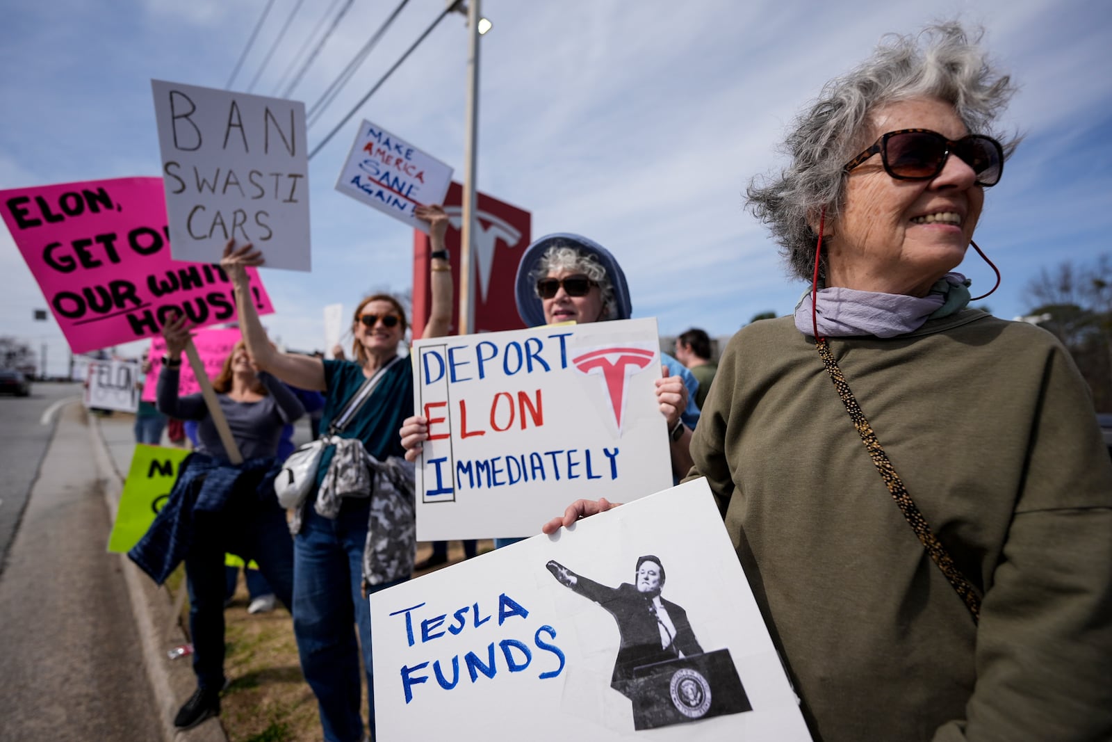 Marsha Partin, right, stands with other demonstrators during a protest of automaker billionaire CEO, Elon Musk near a Tesla vehicle dealership, Saturday, March 8, 2025, in Decatur, Ga. (AP Photo/Mike Stewart)