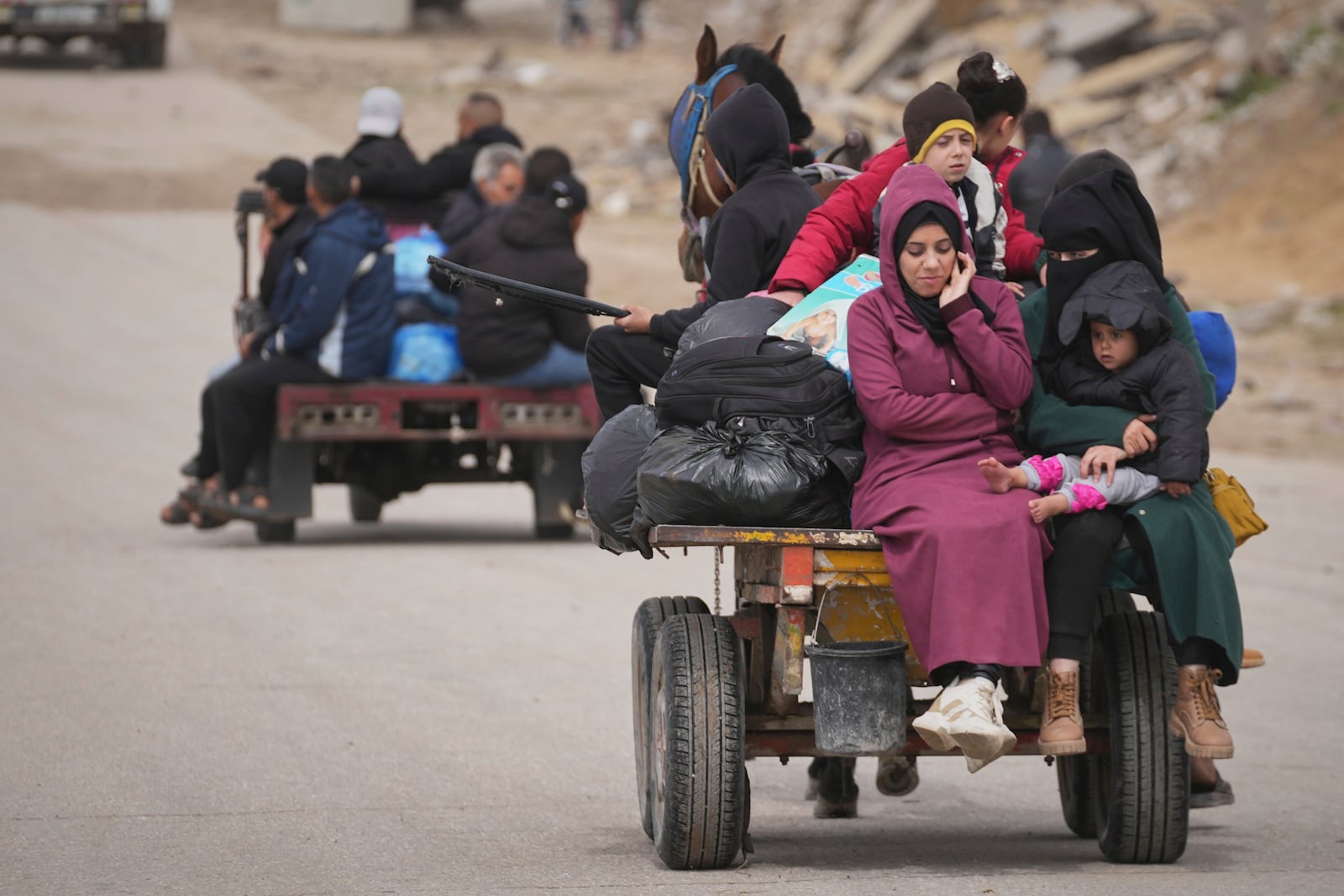 Displaced Palestinians, carrying their belongings and other items, move between southern and northern Gaza along a beach road away from the areas where the Israeli army is operating after Israel's renewed offensive in the Gaza Strip, in the outskirts of Gaza City, Friday March 21, 2025. (AP Photo/Abdel Kareem Hana)