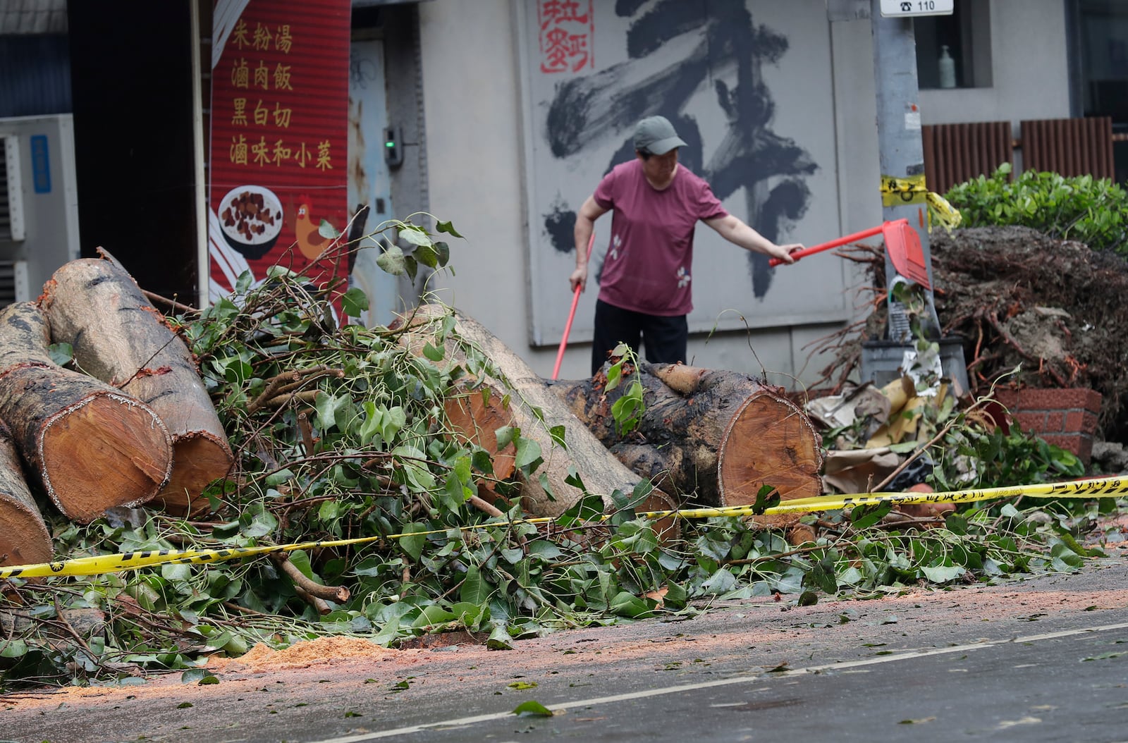 A woman clears debris in the aftermath of Typhoon Kong-rey in Taipei, Taiwan, Friday, Nov. 1, 2024. (AP Photo/Chiang Ying-ying)