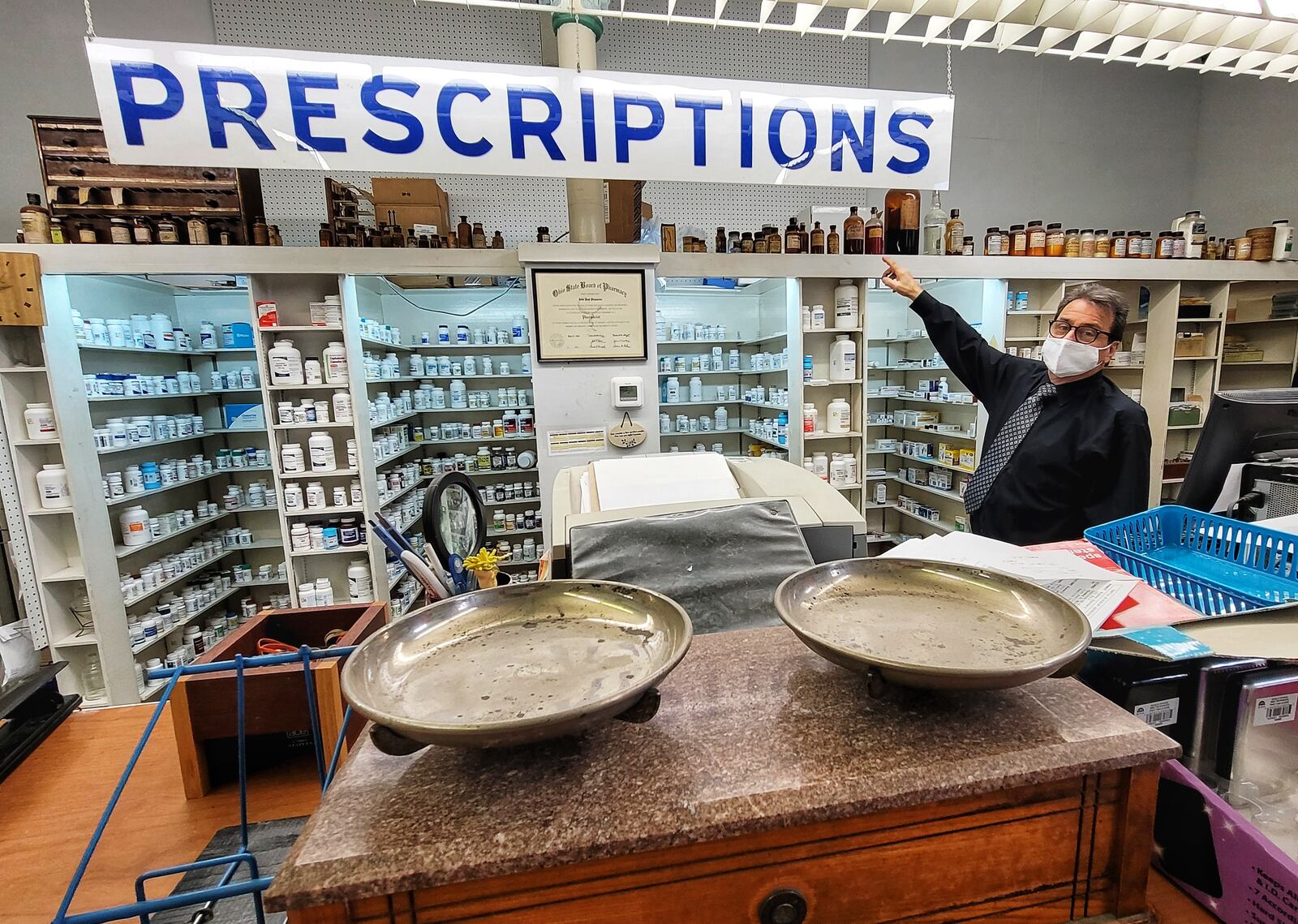 Pharmacist Jim Fescina shows some of the historic items on display in Hughes Pharmacy Wednesday, January 27, 2021. Hughes Pharmacy, a business that has been in Hamilton for over 100 years, will close its doors permanently on Saturday. NICK GRAHAM / STAFF