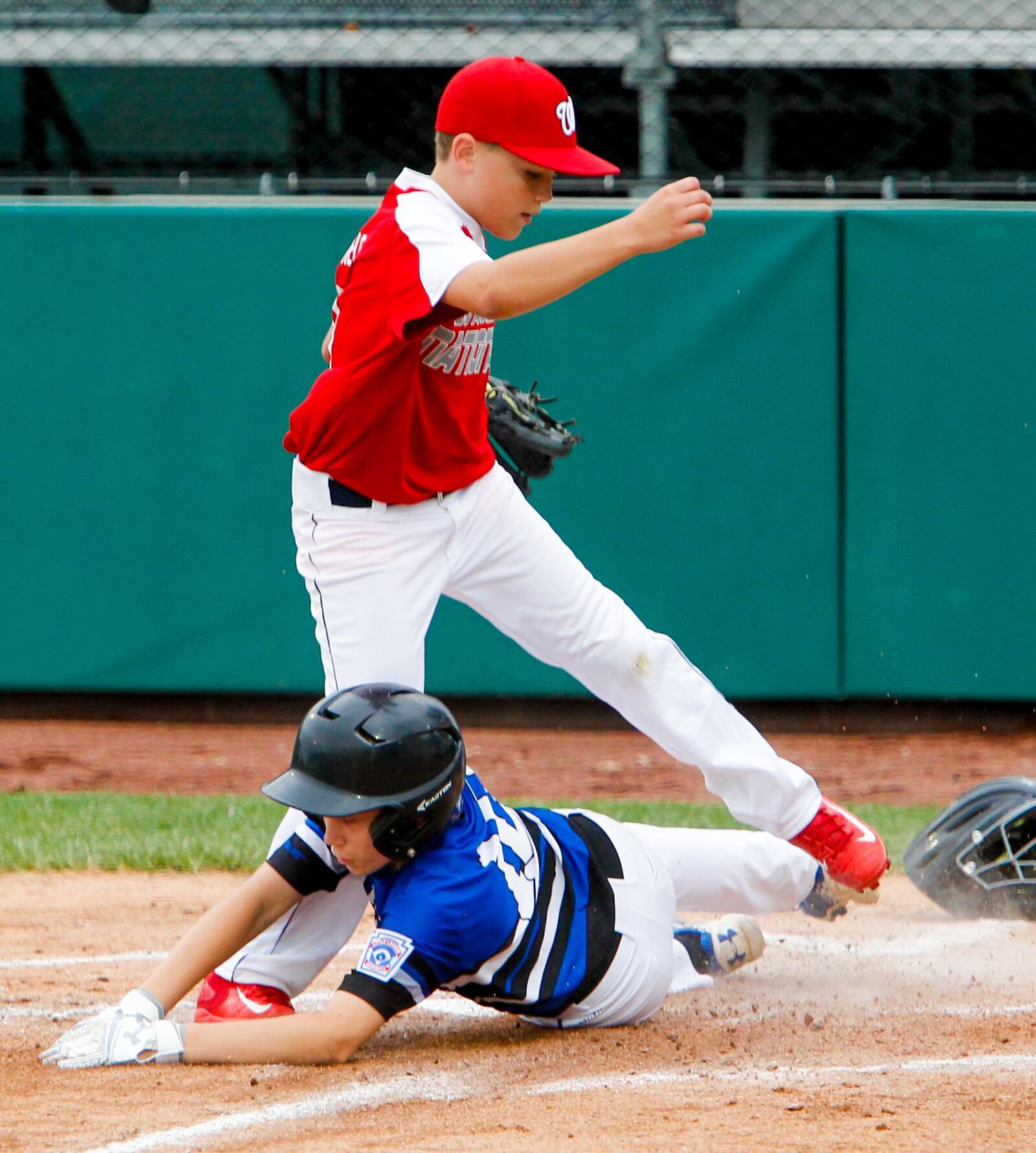 Hamilton West Side’s Jared Halupnik (10) scores on a passed ball as Wausau National (Wis.) pitcher Keagan Jirschele (11) can’t get there in time during their Little League Great Lakes Regional game at Grand Park Sports Campus in Westfield, Ind., on Sunday. GREG LYNCH/STAFF