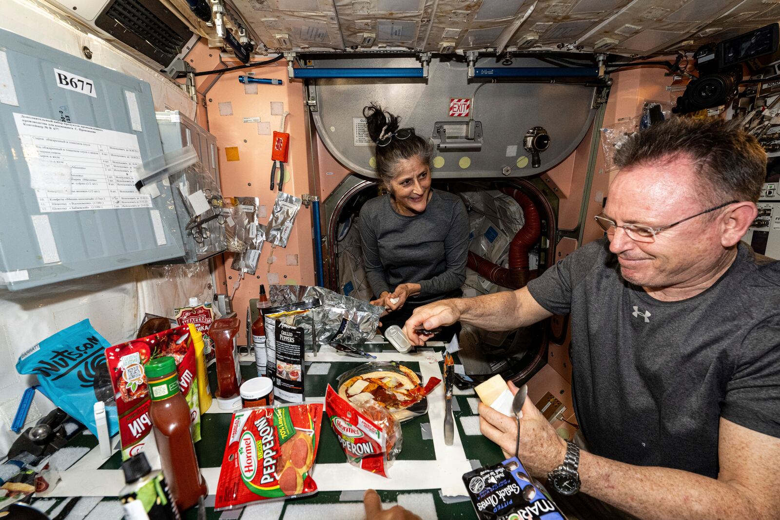 FILE - In this photo released by NASA, astronauts Suni Williams and Butch Wilmore, both Expedition 71 Flight Engineers, make pizza aboard the International Space Station's galley located inside the Unity module on Sept. 9, 2024. Items are attached to the galley using tape and velcro to keep them from flying away in the microgravity environment. (NASA via AP, File)