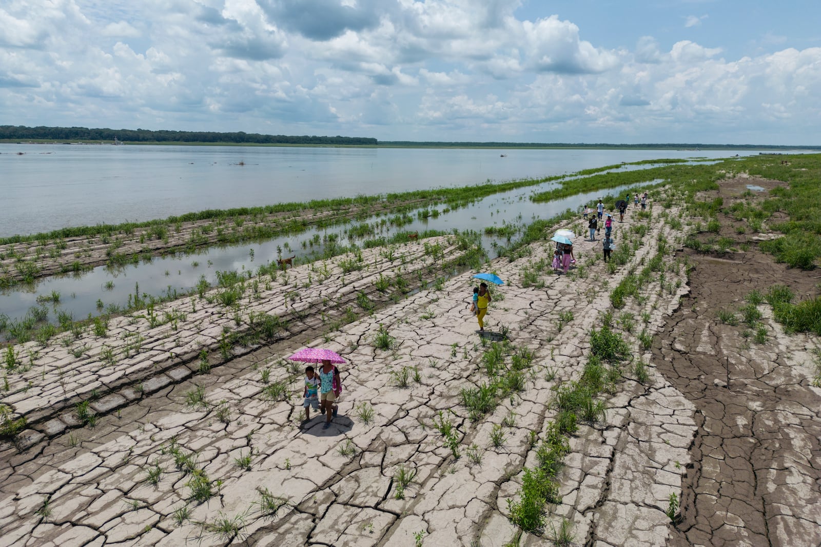 People walk through a part of the Amazon River that shows signs of drought in Santa Sofia, on the outskirts of Leticia, Colombia, Sunday, Oct. 20, 2024. (AP Photo/Ivan Valencia)