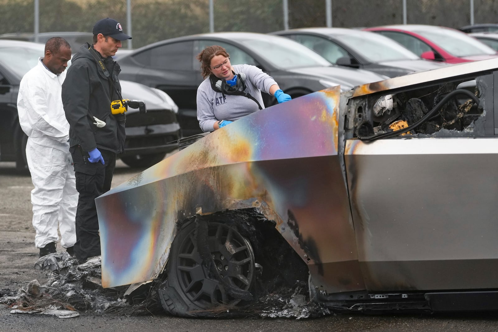 ATF investigators and a member of the Seattle Fire Department inspect burned Tesla Cybertrucks at a Tesla lot in Seattle, Monday, March 10, 2025. (AP Photo/Lindsey Wasson)