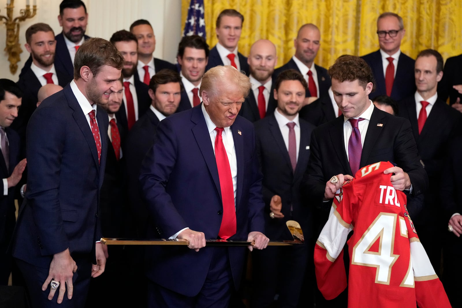 President Donald Trump holds a hockey stick as he poses for a photo with Aleksander Barkov, left, and Matthew Tkachuk during a ceremony with the Florida Panthers NHL hockey team to celebrate their 2024 Stanley Cup win, in the East Room of the White House, Monday, Feb. 3, 2025, in Washington. (AP Photo/Alex Brandon)