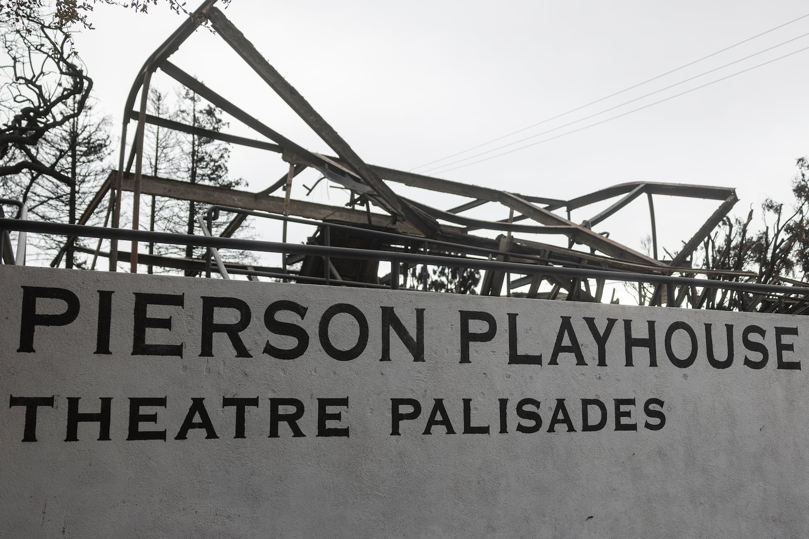 Signage is displayed the parking lot of the Theatre Palisades, which was destroyed by the Palisades Fire, in the Pacific Palisades neighborhood of Los Angeles, Calif., Saturday, Jan. 25, 2025. (AP Photo/Etienne Laurent)