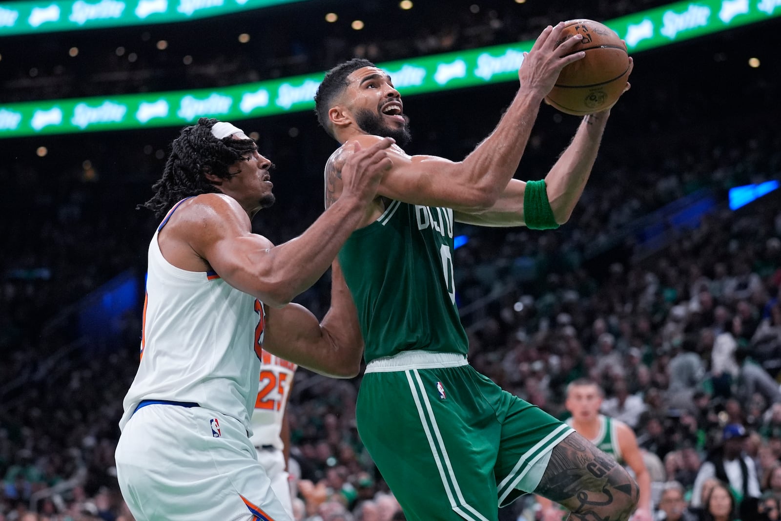 Boston Celtics forward Jayson Tatum, right, drives to the basket past New York Knicks center Jericho Sims, left, during the second half of an NBA basketball game, Tuesday, Oct. 22, 2024, in Boston. (AP Photo/Charles Krupa)