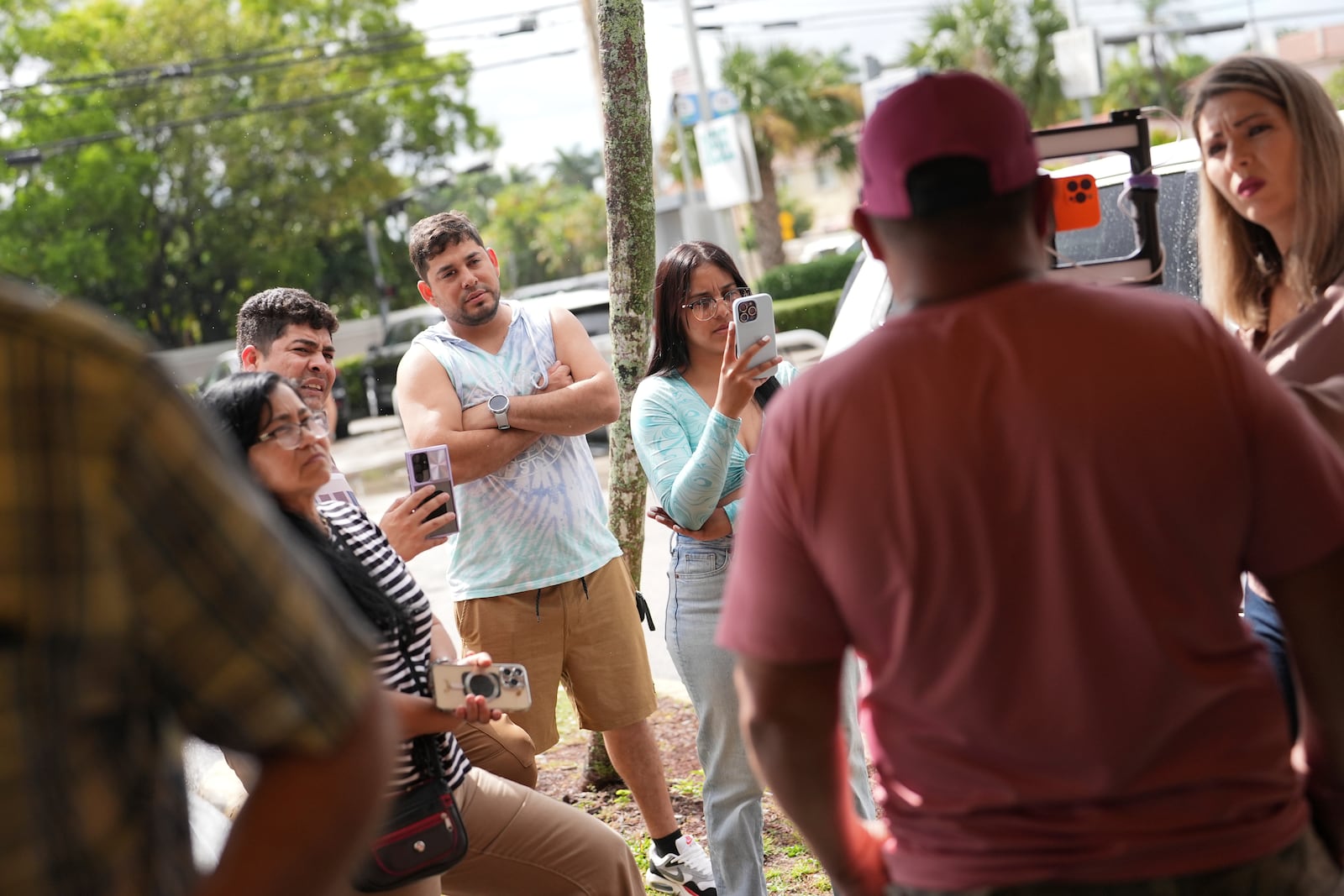 Heidy Carmona, 22, center, films as her father Henry Carmona, who fled Venezuela after receiving death threats for refusing to participate in demonstrations in support of the government, talks to a reporter following a press conference by Venezuelan community leaders to denounce changes to the protections that shielded hundreds of thousands of Venezuelans, including the 48-year-old Carmona, from deportation, Monday, Feb. 3, 2025, in Doral, Fla. (AP Photo/Rebecca Blackwell)