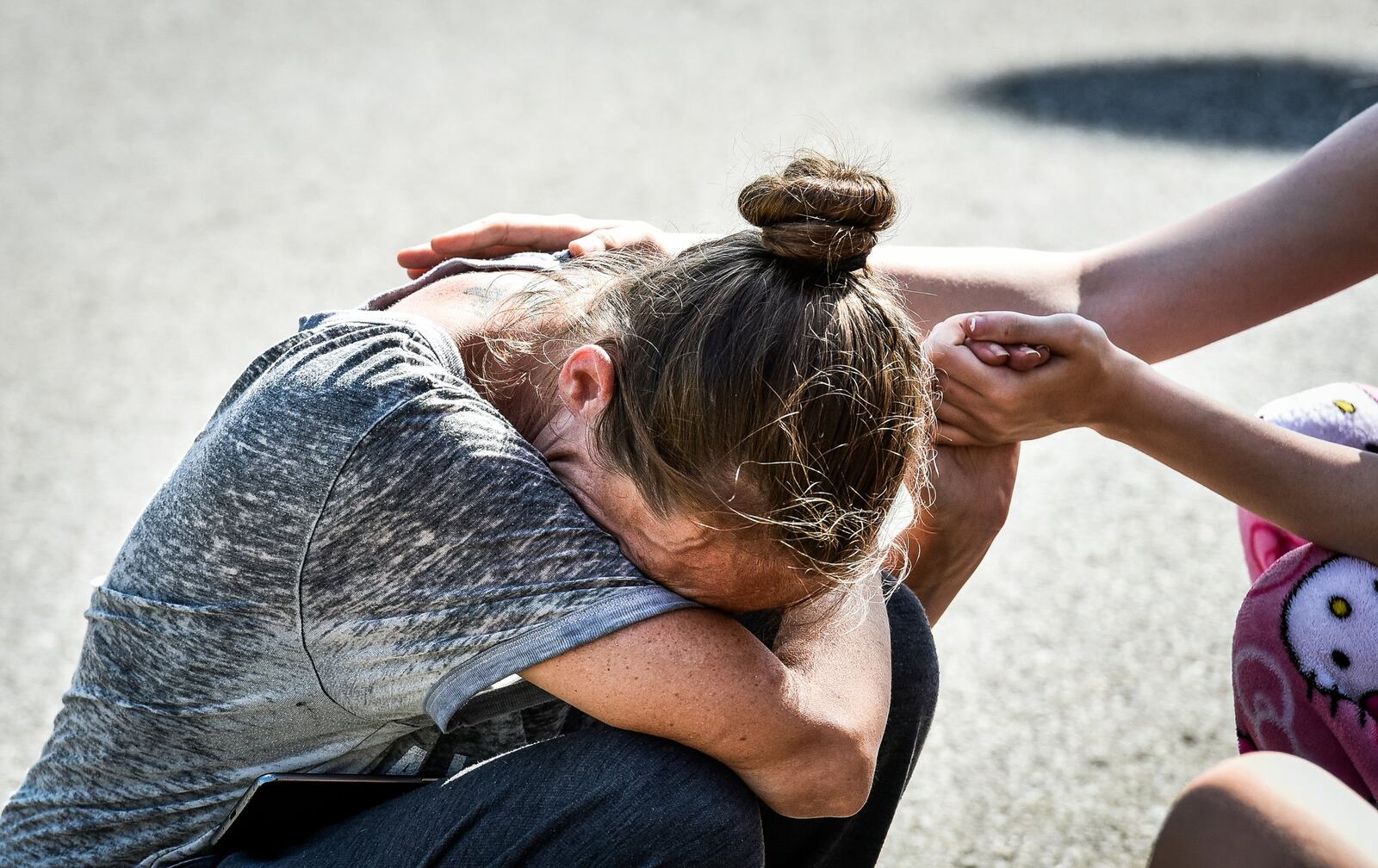 Amanda Proffitt, who tried to help Davis after he was shot, kneels at a memorial  May 30 on Woodlawn Avenue in Middletown. 