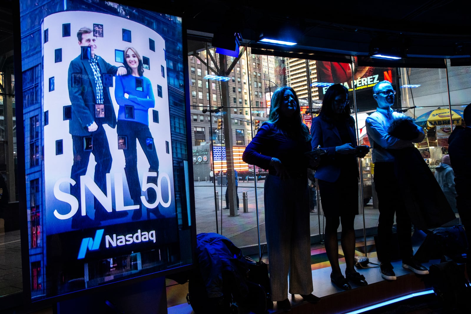 People watch current and veteran members of the SNL cast celebrate the SNL IPO as they ring the Nasdaq opening bell, in New York's Times Square, Thursday, Feb. 14, 2025. (AP Photo/Eduardo Munoz Alvarez)