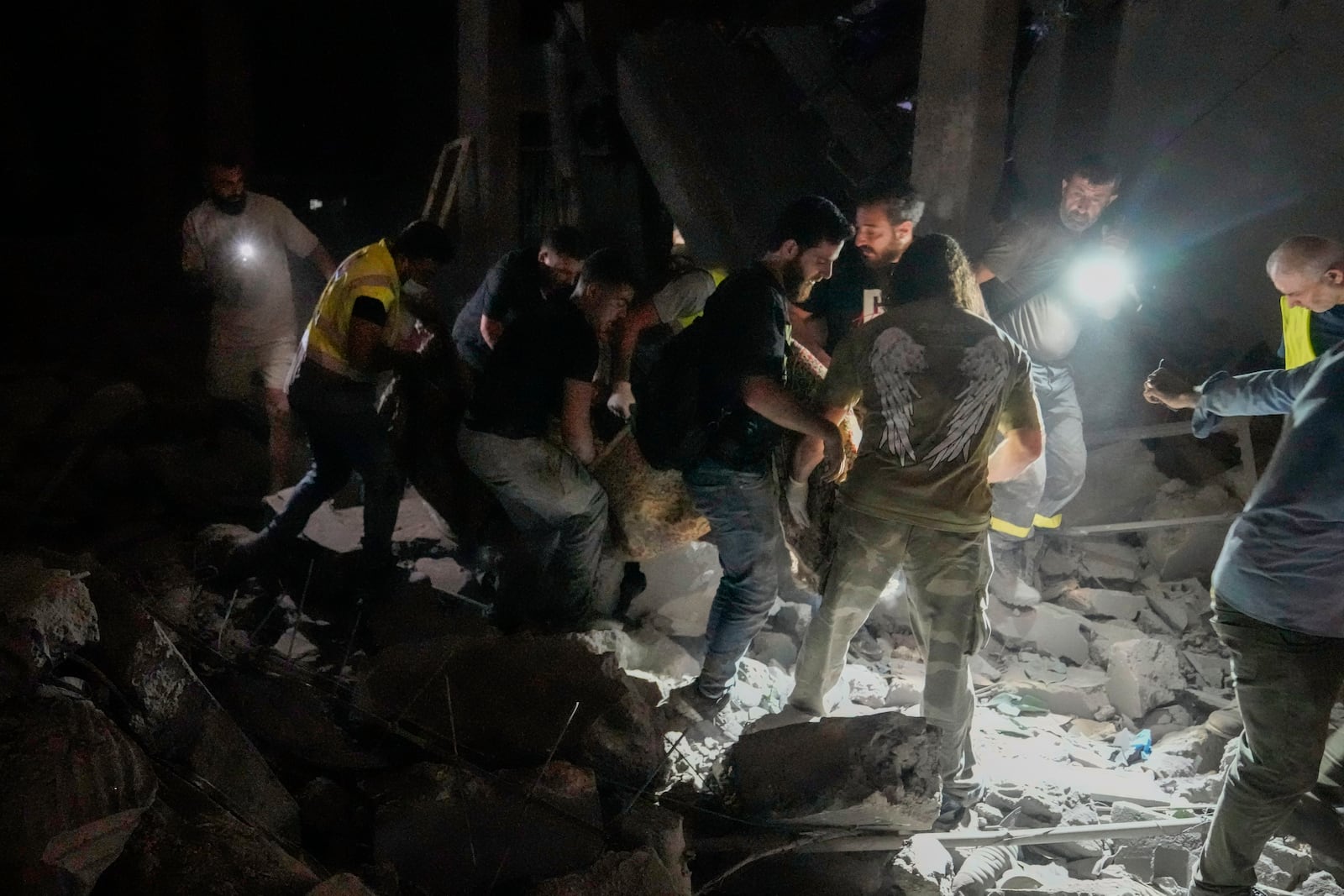 People carry a body at the scene of destroyed buildings hit by an Israeli airstrike in central Beirut, Lebanon, Thursday, Oct. 10, 2024. (AP Photo/Bilal Hussein)