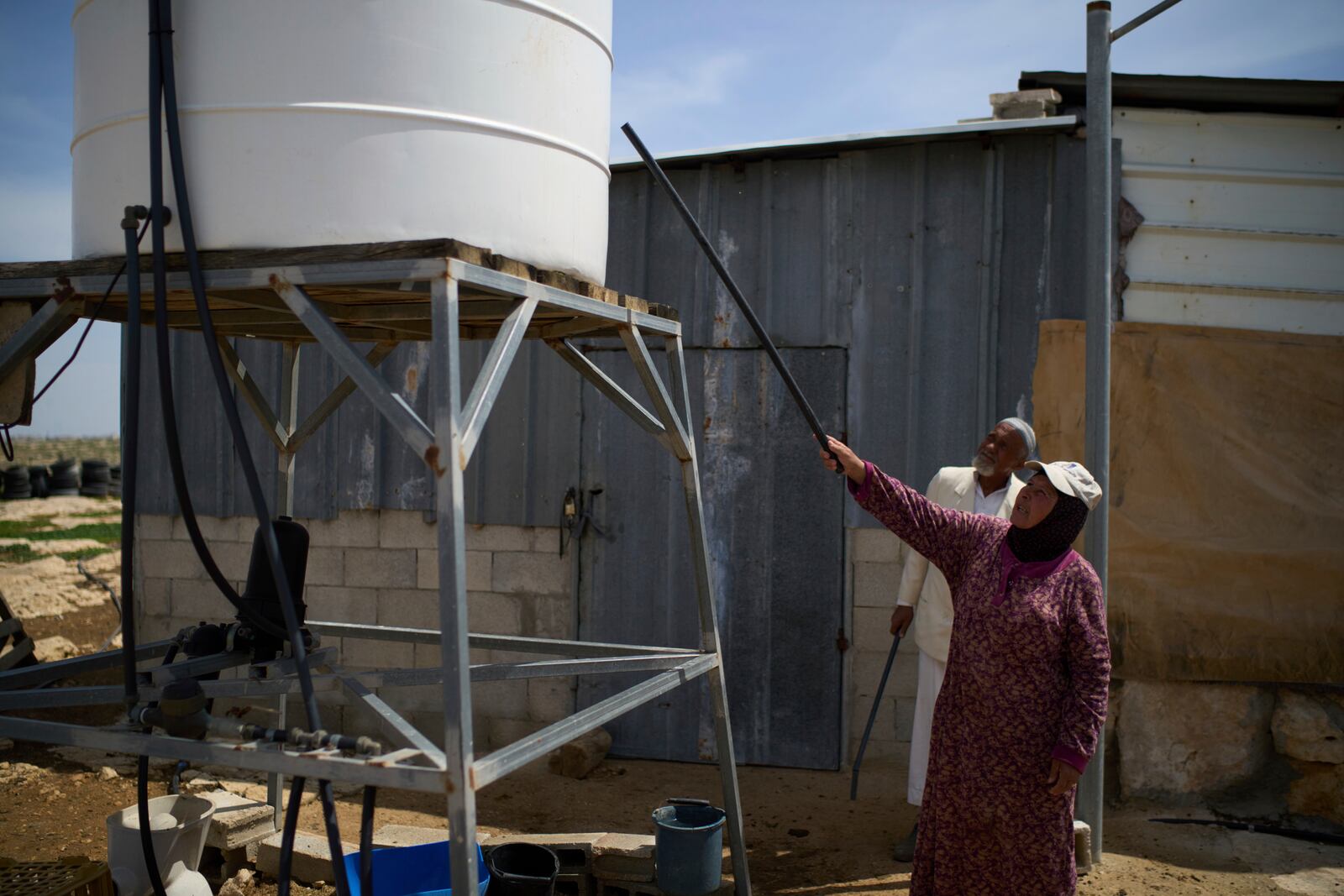 Muhammad Mughanem and his wife Najah show their damaged water tank following a settler's attack in the village of Susiya in Masafer Yatta, south Hebron hills Tuesday, March 25, 2025. (AP Photo/Leo Correa)