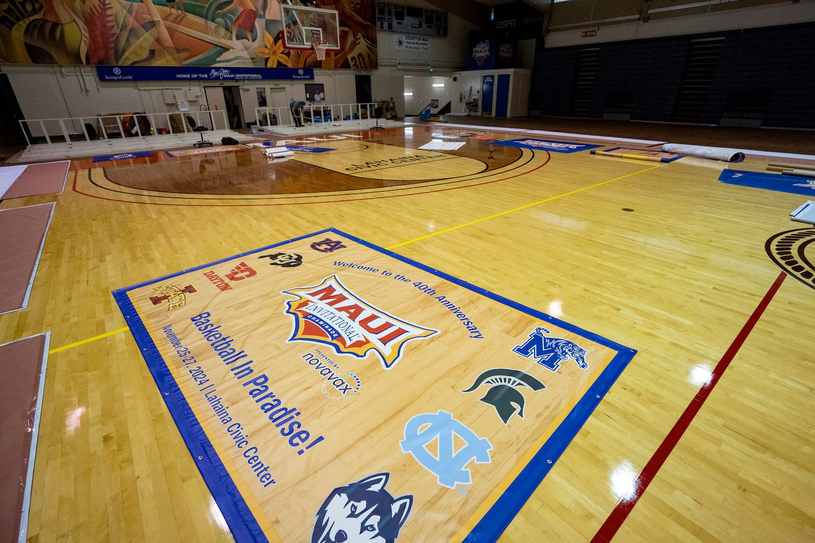 Workers set up banners and signs at Lahaina Civic Center, the venue for the Maui Invitational, Monday, Nov. 18, 2024, in Lahaina, Hawaii. The Maui Invitational is back in Lahaina, where eight of the NCAA's top men's basketball teams will compete in a three-day tournament. (AP Photo/Mengshin Lin)