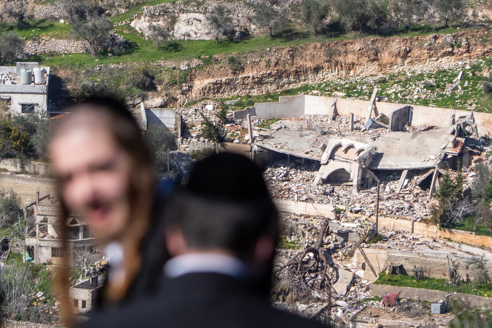 Ultra-Orthodox Jewish men look from Kibbutz Misgav Am in northern Israel at the village of Odaisseh in Southern Lebanon after Israeli forces withdrew from border villages , Tuesday, Feb. 18, 2025. (AP Photo/Ariel Schalit)