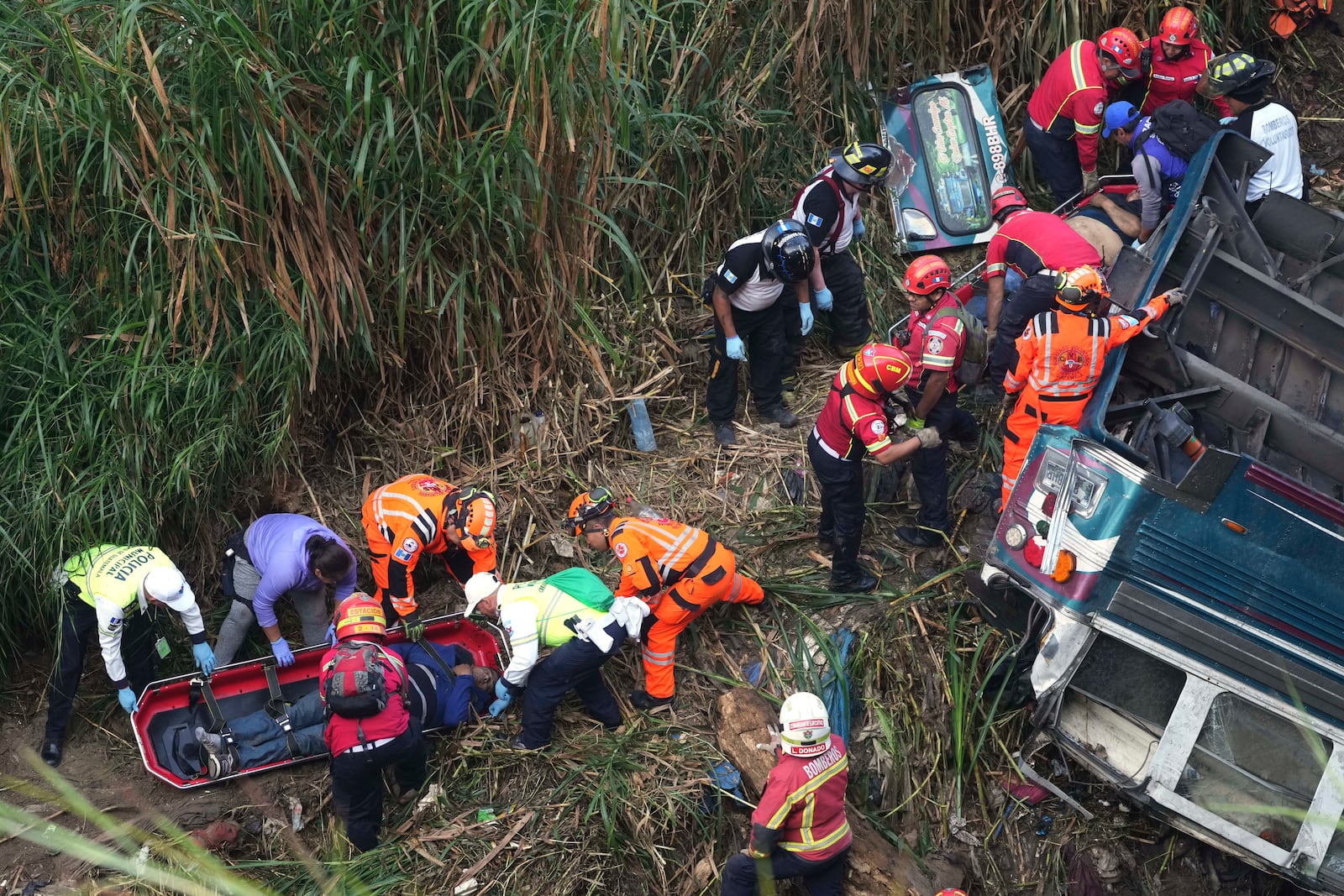 Firefighters work at the scene of a bus that fell from a bridge on the outskirts of Guatemala City, Monday, Feb. 10, 2025. (AP Photo/Moises Castillo)