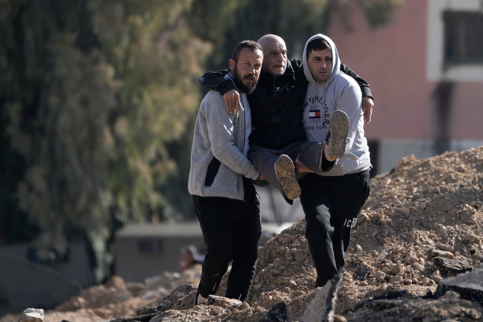 Palestinians displaced by an Israeli military operation from the Jenin refugee camp in the West Bank carry an elderly man over rubble on Thursday, Jan. 23, 2025. (AP Photo/Majdi Mohammed)