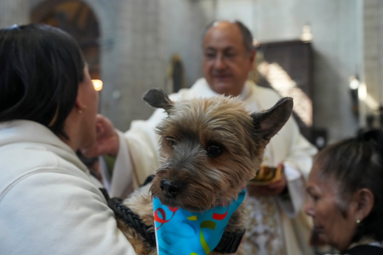 Gabriela Viquez holds onto her black and tan Yorkie Jerome, as she receives communion during the annual blessing of the animals Mass in Mexico City's Metropolitan Cathedral, Friday, Jan. 17, 2025. (AP Photo/Marco Ugarte)