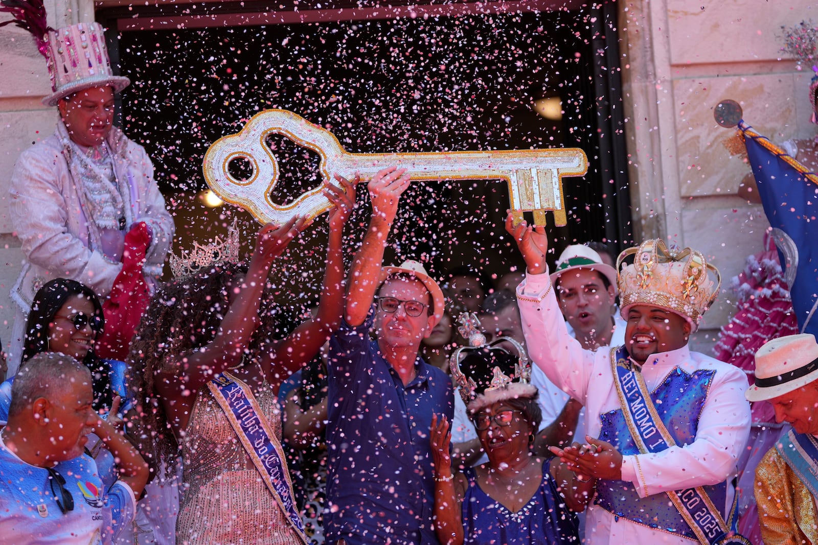 Carnival King Momo, Kaio Mackenzie, right, with Queen Thuane de Oliveira, hold up the keys of the city from Mayor Eduardo Paes, center, at a ceremony officially kicking off Carnival in Rio de Janeiro, Brazil, Friday, Feb. 28, 2025. (AP Photo/Silvia Izquierdo)