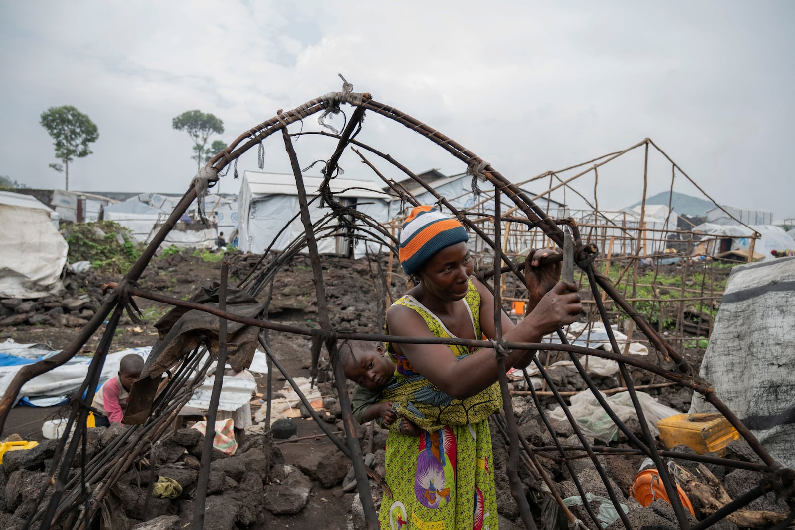 A woman and her child who were displaced by the fighting between M23 rebels and government soldiers prepare to leave the camp following an instruction by M23 rebels in Goma, Democratic Republic of the Congo, Tuesday, Feb. 11, 2025. (AP Photo/Moses Sawasawa)