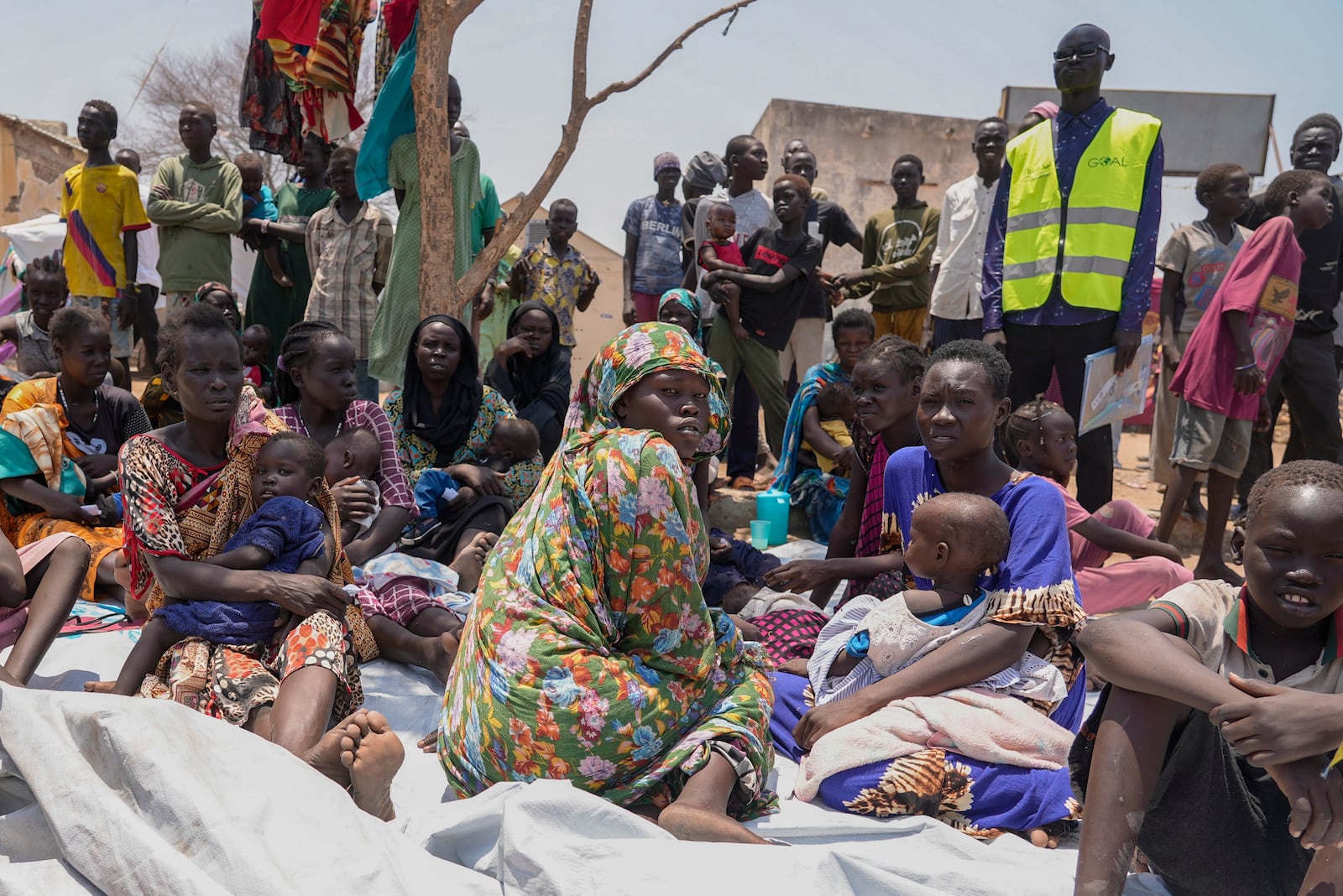 FILE - South Sudanese people sit outside a nutrition clinic at a transit center in Renk, South Sudan, on May 16, 2023. (AP Photo/Sam Mednick, File)