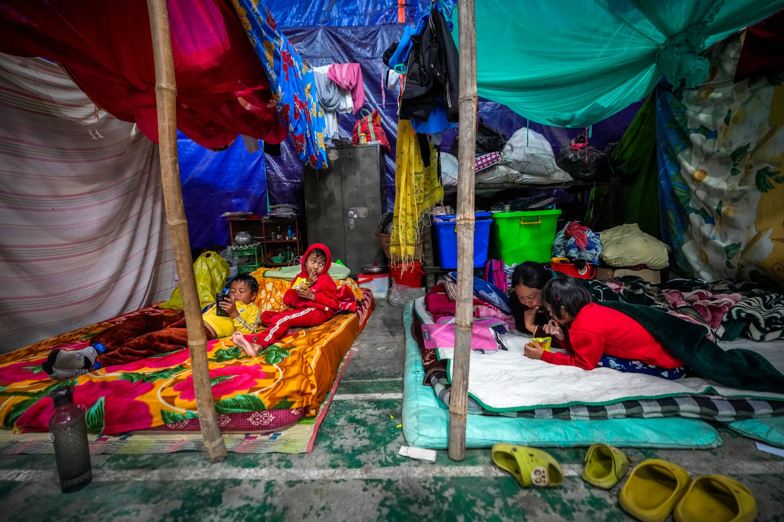 A Meitei woman and children take rest in a relief camp in Imphal, Manipur, Monday, Dec. 16, 2024. (AP Photo/Anupam Nath)