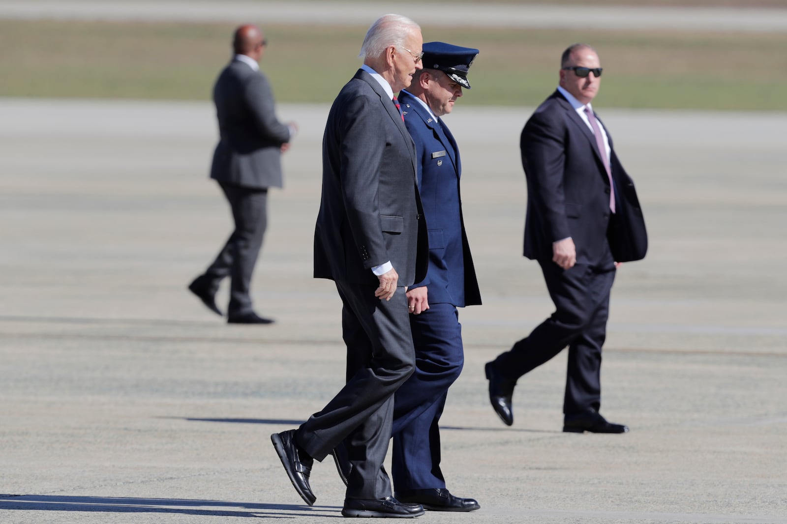 President Joe Biden, center left, is escorted by Col. Paul Pawluk, Vice Commander, 89th Airlift Wing, center right, as he walks from Marine One before boarding Air Force One at Joint Base Andrews, Md., Tuesday, Oct. 22, 2024. (AP Photo/Luis M. Alvarez)