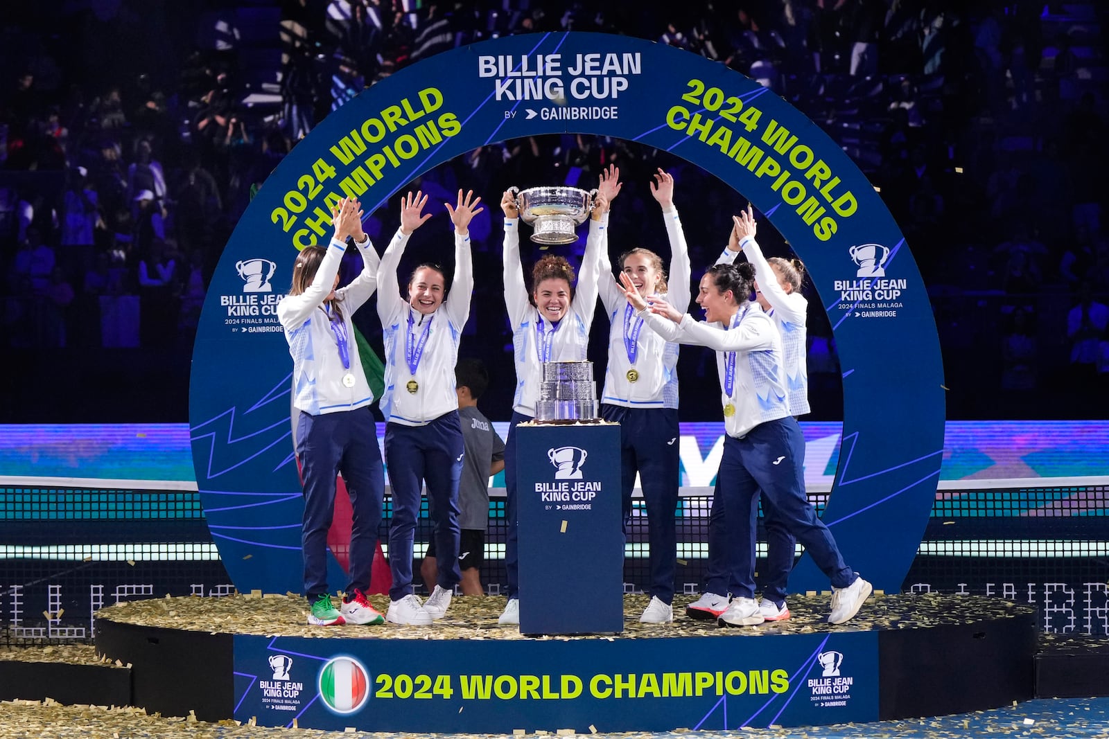 Italy's tennis team celebrates on the podium after winning the Billie Jean King Cup final against Slovakia at the Martin Carpena Sports Hall in Malaga, southern Spain, on Wednesday, Nov. 20, 2024. (AP Photo/Manu Fernandez)