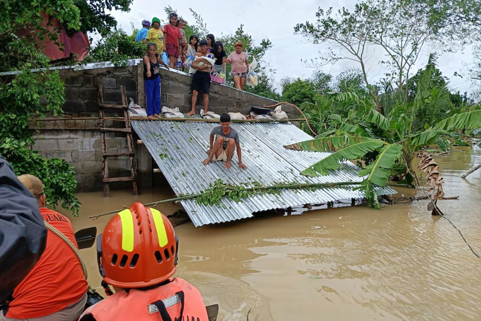 In this photo provided by the Philippine Coast Guard, residents staying on top of their roofs to avoid floods caused by Tropical Storm Trami, locally named Kristine, await to be rescued at Libon, Albay province, Philippines on Wednesday Oct. 23, 2024. (Philippine Coast Guard via AP)