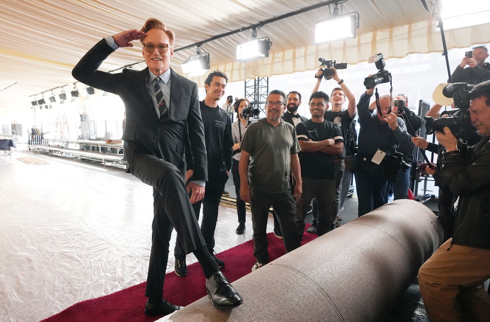 Conan O'Brien, left, host of Sunday's 97th Academy Awards, salutes photographers before helping to roll out the red carpet at the Dolby Theatre on Wednesday, Feb. 26, 2025, in Los Angeles. (AP Photo/Chris Pizzello)