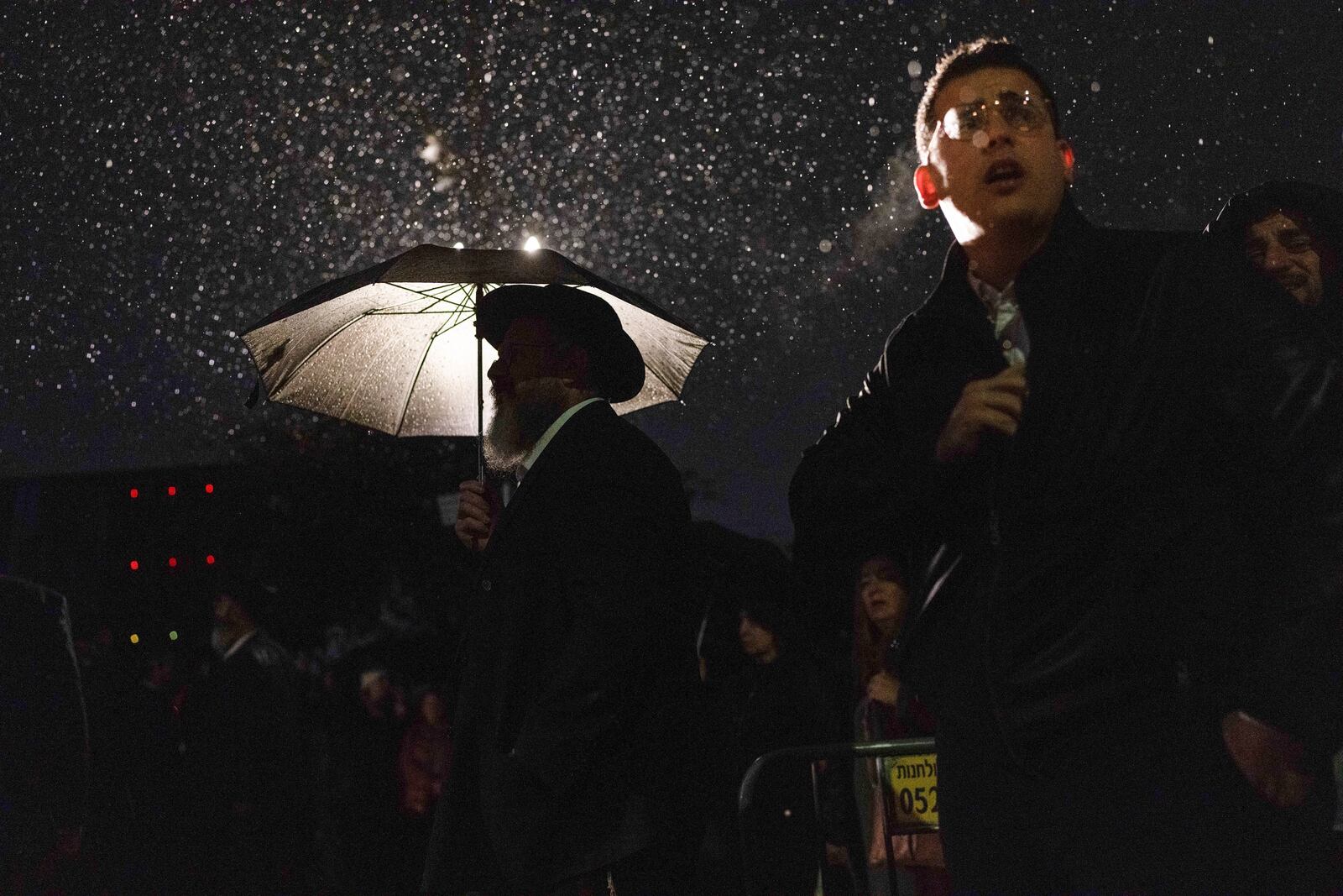 Attendants listen under the rain as a rabbi delivers an eulogy during a ceremony prior to the funeral of Israeli-Moldovan rabbi Zvi Kogan in Kfar Chabad, Israel, Monday Nov. 25, 2024. Kogan, 28, an ultra-Orthodox rabbi, was killed last week in Dubai where he ran a kosher grocery store. Israelis have flocked for commerce and tourism since the two countries forged diplomatic ties in the 2020 Abraham Accords.(AP Photo/Ohad Zwigenberg)