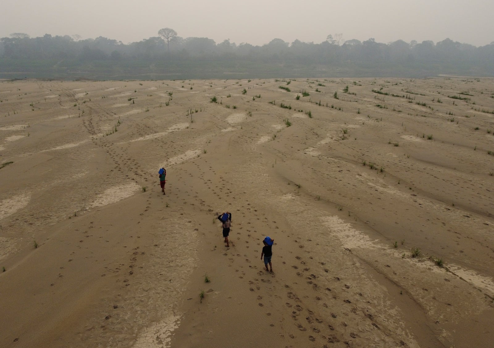 FILE - Residents transport drinking water from Humaita to the Paraizinho community, along the dry Madeira River, a tributary of the Amazon River, amid a drought, Amazonas state, Brazil, Sunday, Sept. 8, 2024. (AP Photo/Edmar Barros, File)