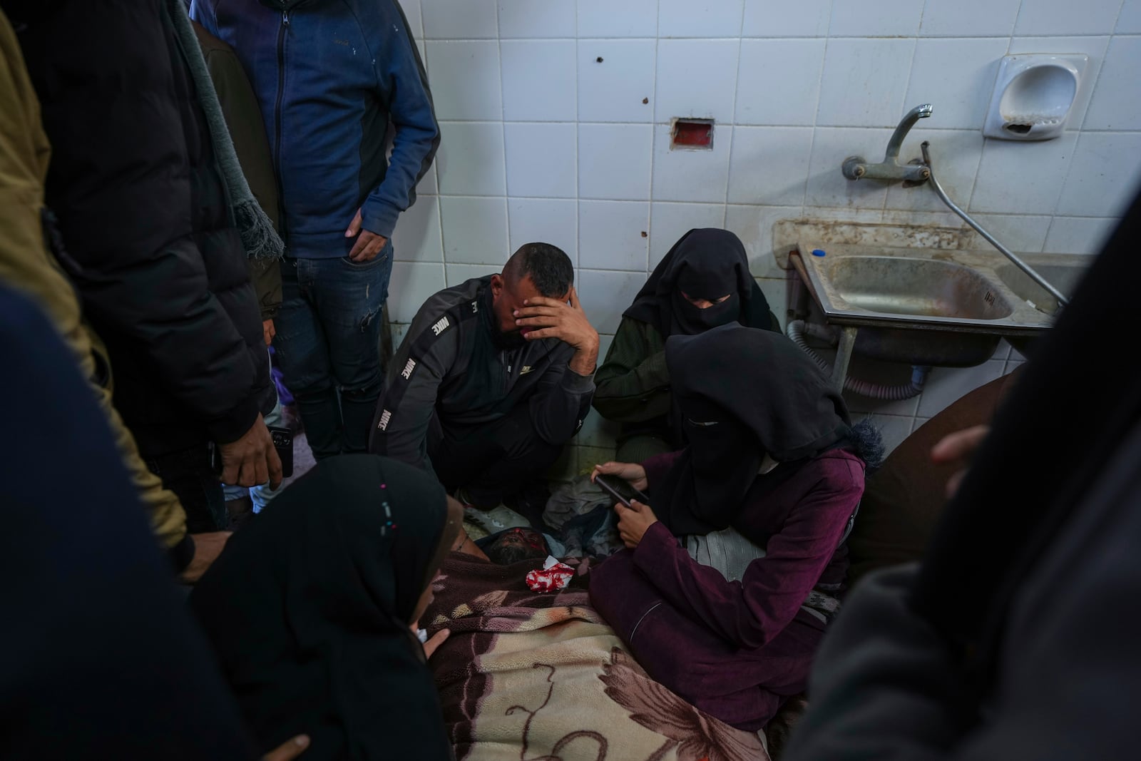 Relatives react next to the body of a Palestinian who was killed in the Israeli bombardment of the Gaza Strip at Al-Aqsa Hospital in Deir al-Balah, Wednesday, Jan. 15, 2025. (AP Photo/Abdel Kareem Hana)