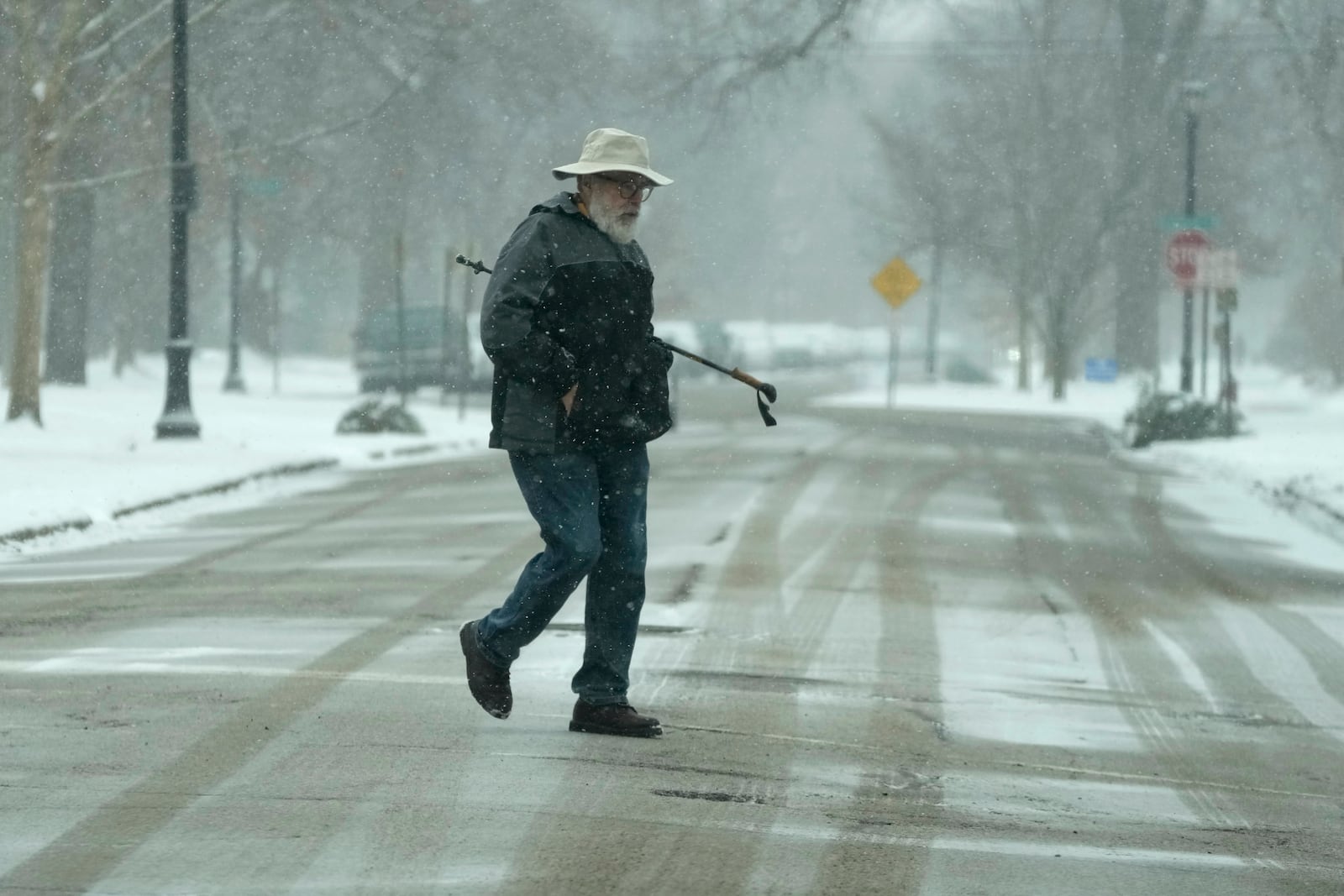 Pedestrian crosses the snow-covered street during a snow day in Evanston, Ill., Sunday, Jan. 12, 2025. (AP Photo/Nam Y. Huh)