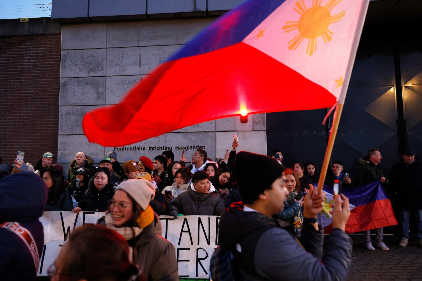 Supporters of former Philippine President Rodrigo Duterte hold flags and banners during a demonstration outside the International Criminal Court detention center near The Hague in Scheveningen, Netherlands, Wednesday, March 12, 2025. (AP Photo/Omar Havana)