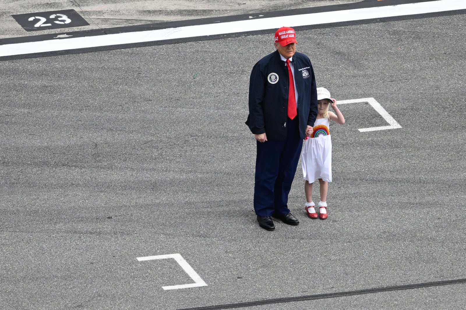 President Donald Trump stands with his granddaughter Carolina on pit lane at before the NASCAR Daytona 500 auto race at Daytona International Speedway, Sunday, Feb. 16, 2025, in Daytona Beach, Fla. (AP Photo/Phelan M. Ebenhack)