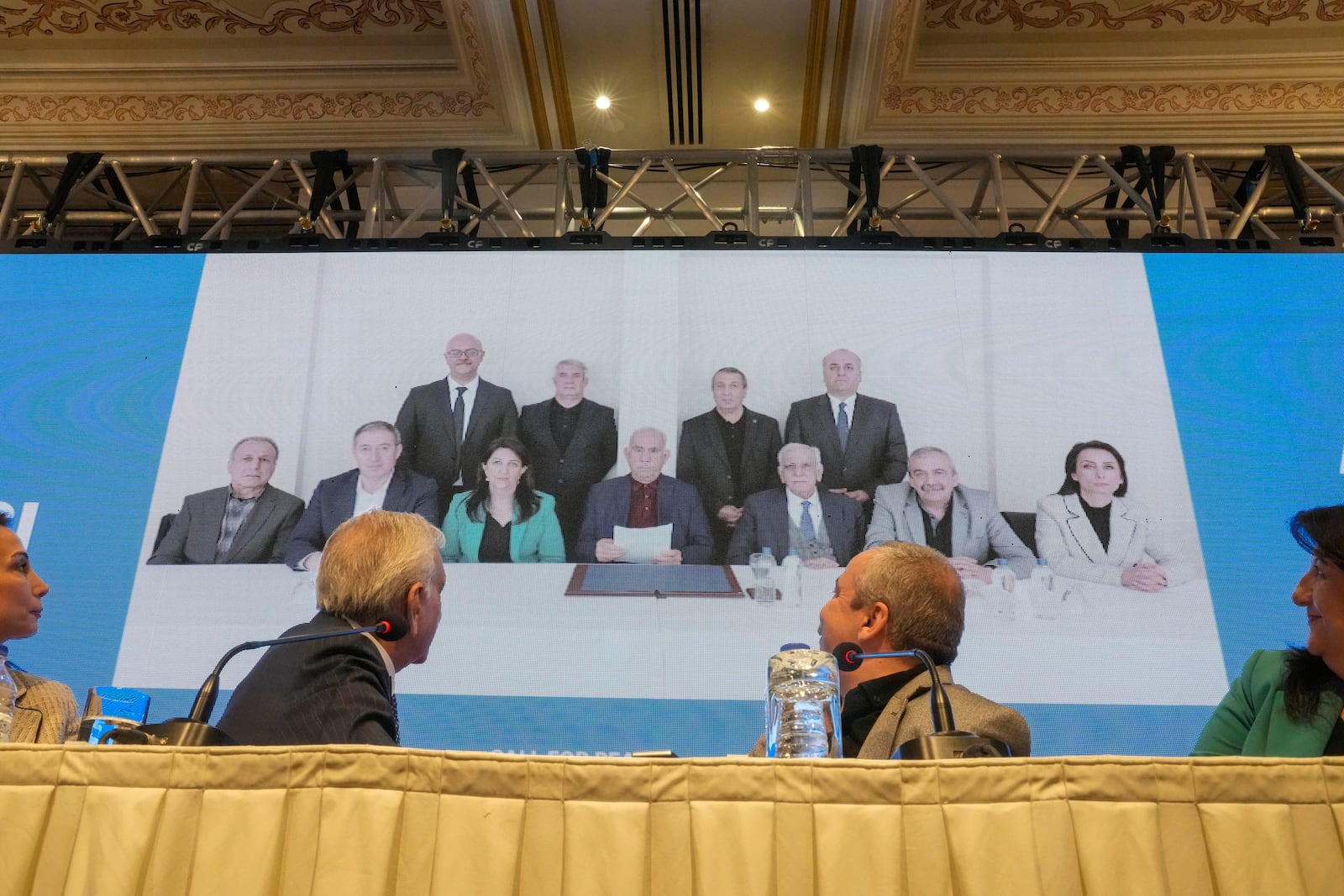 Pro-Kurdish Peoples' Equality and Democracy Party, or DEM, delegation members release an statement from the jailed leader of the rebel Kurdistan Workers' Party, or PKK, Abdullah Ocalan, center at the background photo, in Istanbul, Turkey, Thursday, Feb. 27, 2025. (AP Photo/Khalil Hamra)