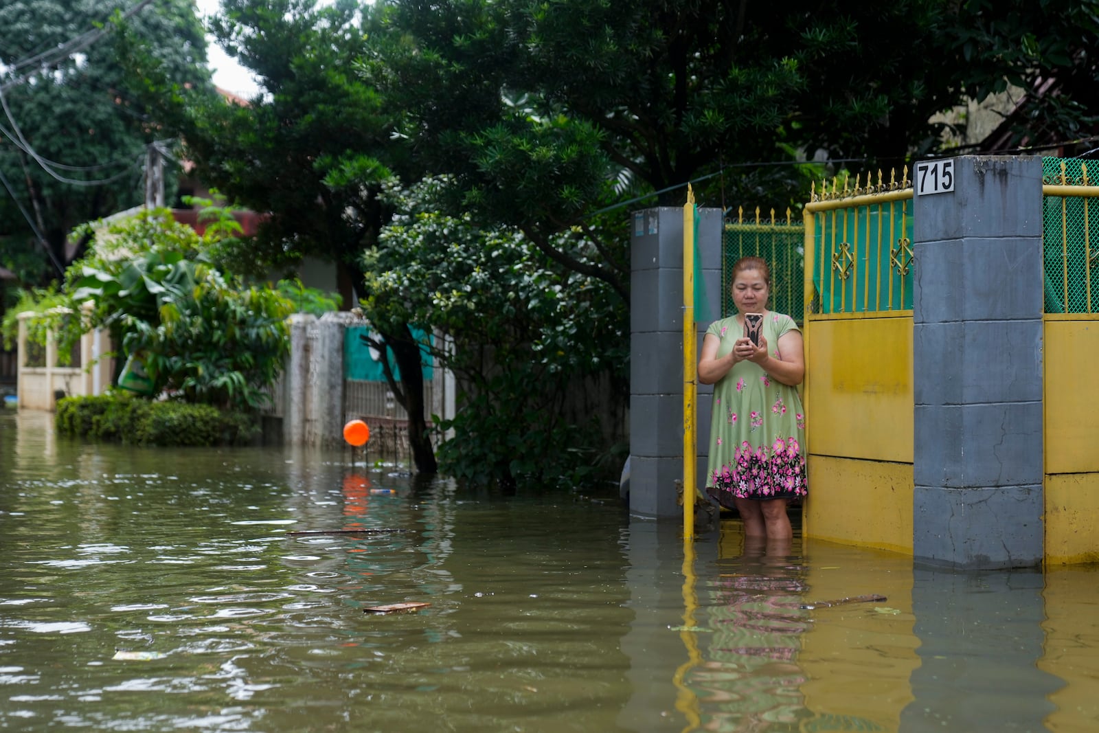 A resident takes pictures of floods caused by Tropical Storm Trami from her home on Friday, Oct. 25, 2024, in Cainta, Rizal province, Philippines. (AP Photo/Aaron Favila)