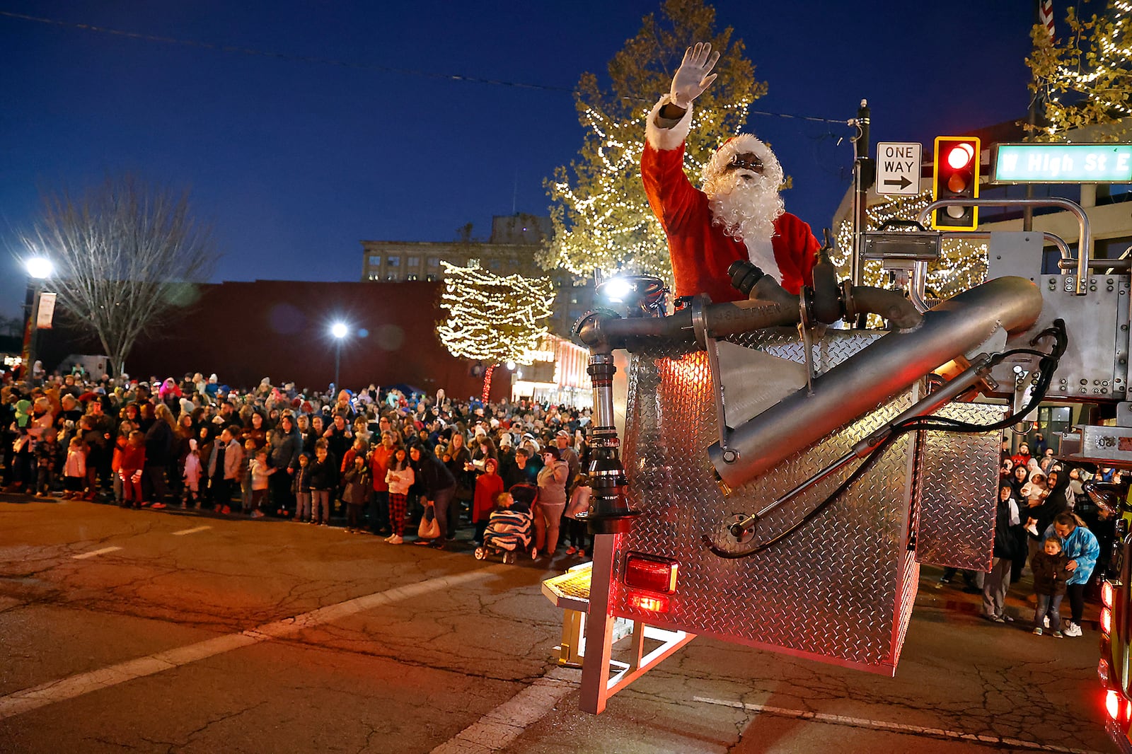 Santa waves to the crowd from the bucket on a Springfield Fire Division aerial truck as he arrives for the Holiday in the City Grand Illumination celebraton Friday, Nov. 25, 2022. BILL LACKEY/STAFF