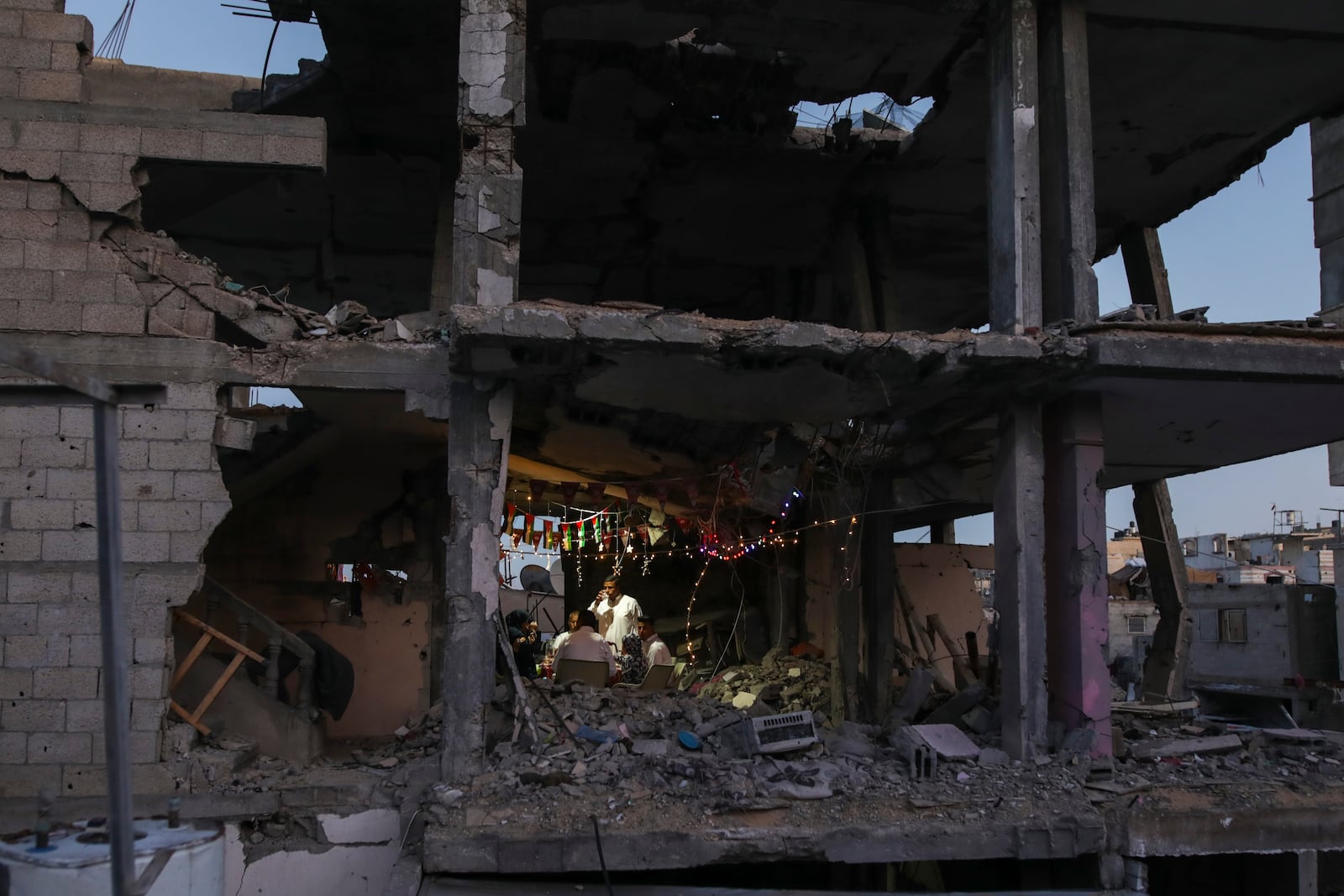 Palestinians have dinner inside their destroyed apartment decorated for the holy month of Ramadan in Khan Younis, southern Gaza Strip, Friday, Feb. 28, 2025. (AP Photo/Jehad Alshrafi)