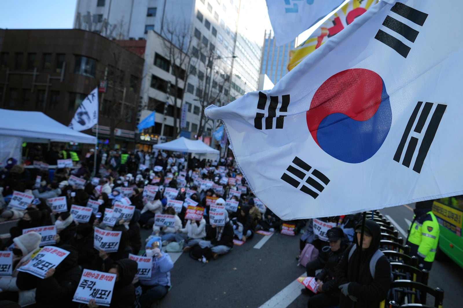 Participants hold signs during a rally calling on the Constitutional Court to dismiss the President Yoon Suk Yeol in Seoul, South Korea, Sunday, Dec. 15, 2024. The signs read "Immediately arrest." (AP Photo/Lee Jin-man)