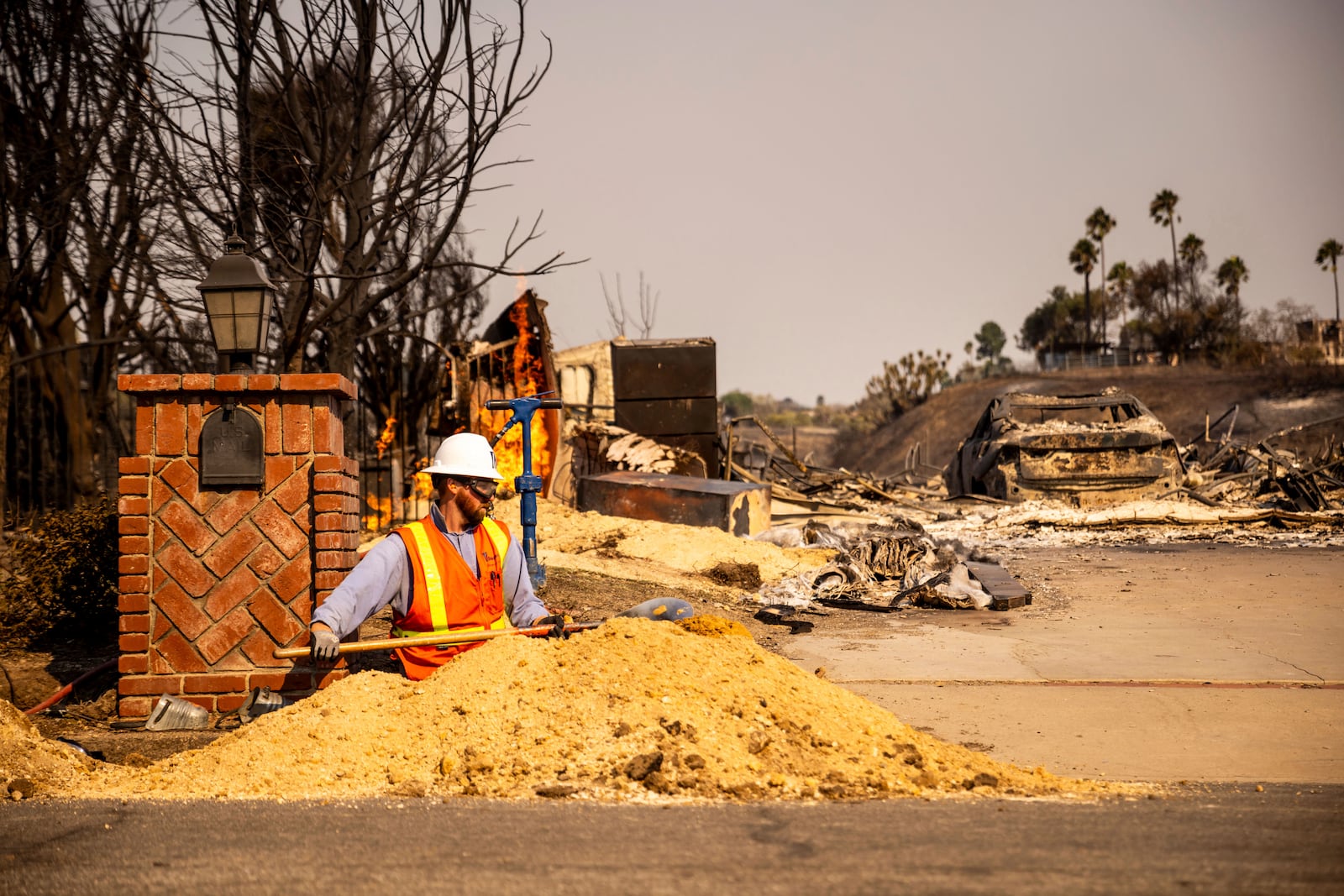 A worker digs a trench in front of a fire-ravaged property after the Mountain Fire swept through, Thursday, Nov. 7, 2024, in Camarillo, Calif. (AP Photo/Ethan Swope)