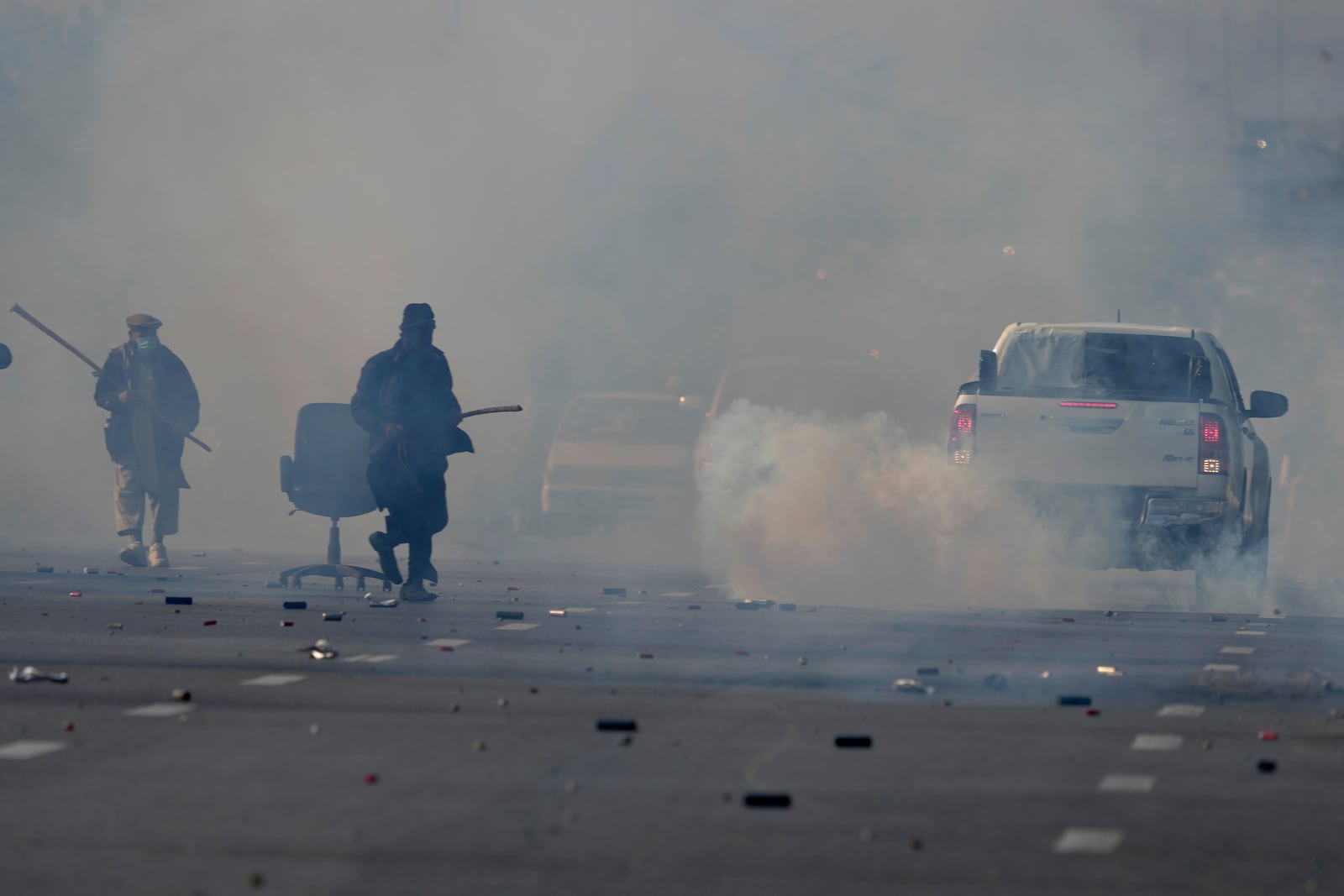 Supporters of imprisoned former Premier Imran Khan's Pakistan Tehreek-e-Insaf party, run for cover as police fire tear gas shell to disperse them during clashes, in Islamabad, Pakistan, Tuesday, Nov. 26, 2024. (AP Photo/Anjum Naveed)