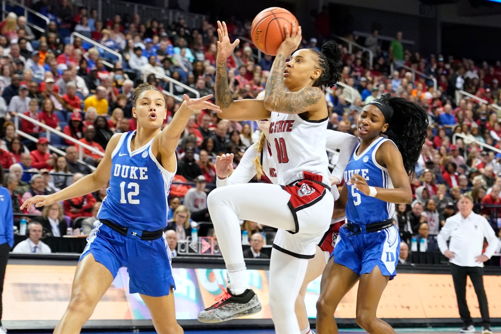 NC State guard Aziaha James (10) drives between Duke forward Delaney Thomas (12) and Duke guard Oluchi Okananwa (5) during an NCAA college basketball game in the championship of the Atlantic Coast Conference tournament Greensboro, N.C., Sunday, March 9, 2025. (AP Photo/Chuck Burton)